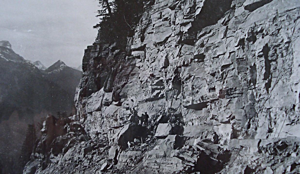 Men on rocky ledge - Going To The Sun Road construction Credit: Glacier Park Archives