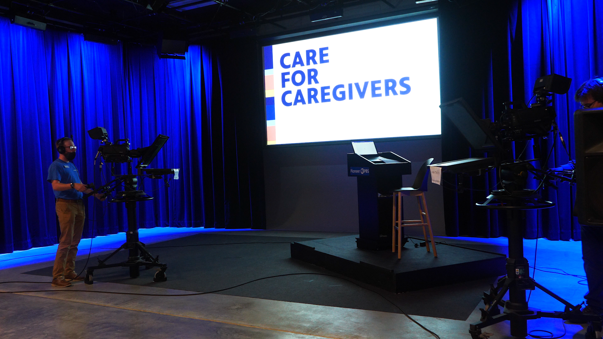 A photo of the Pioneer PBS studio with "Care for Caregivers" on the projection screen.