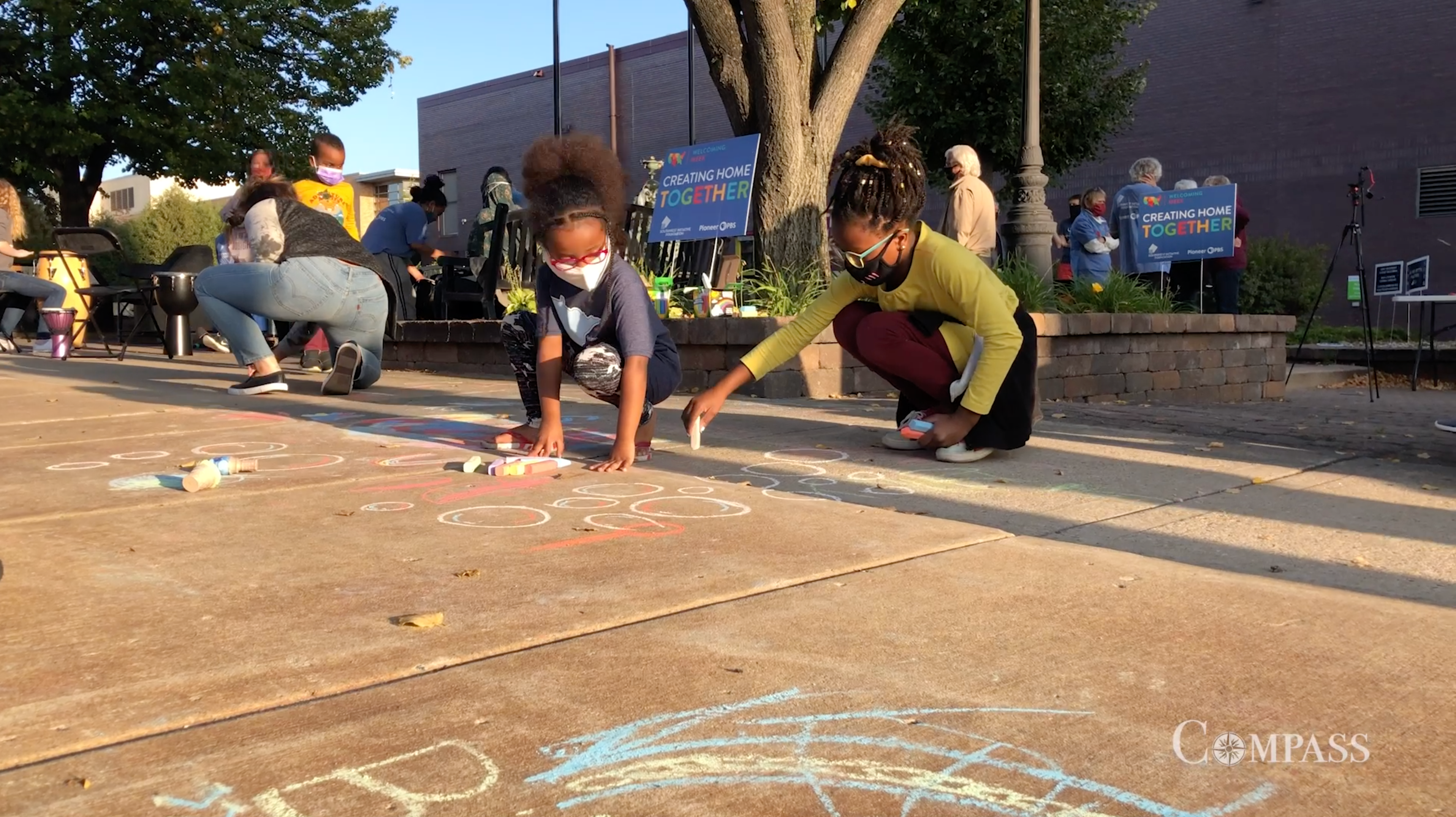 Two girls drawing with chalk on the sidewalk