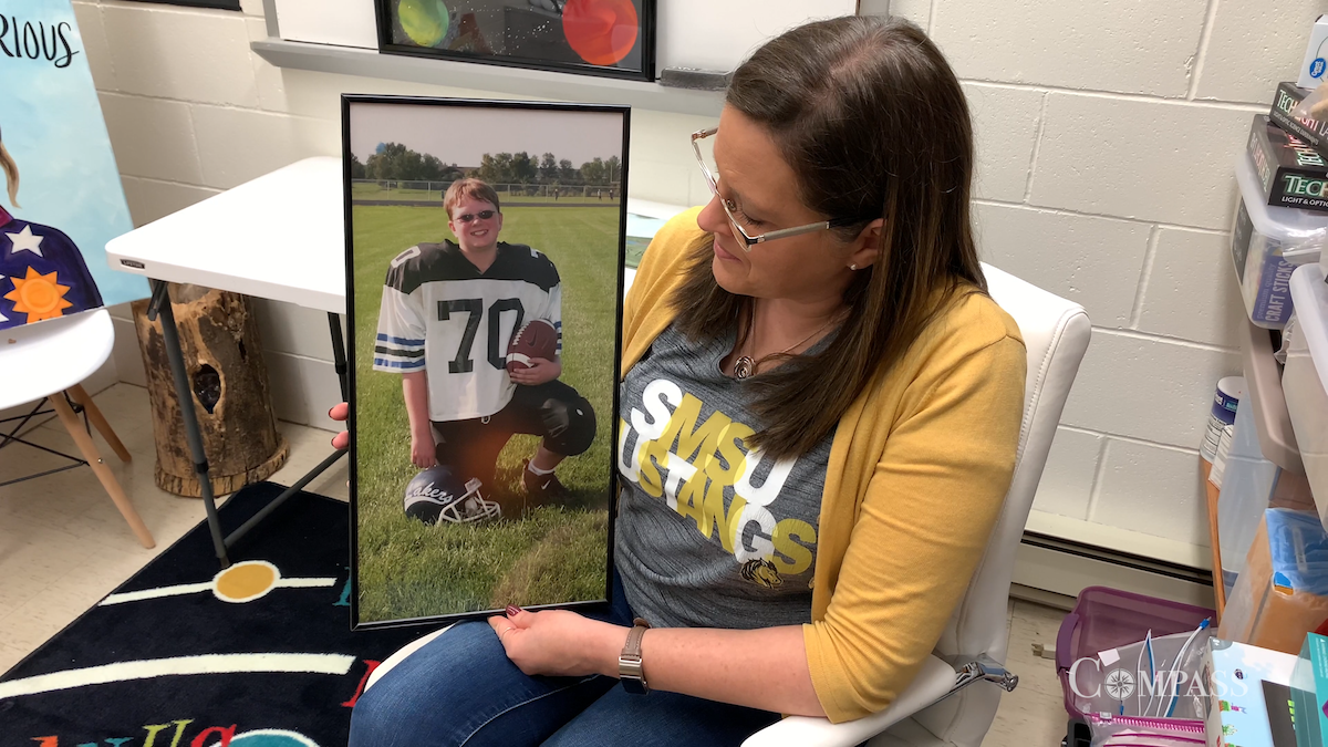 Dr. Kandy Noles Stevens hold a picture of her now deceased son Reed in a football uniform.
