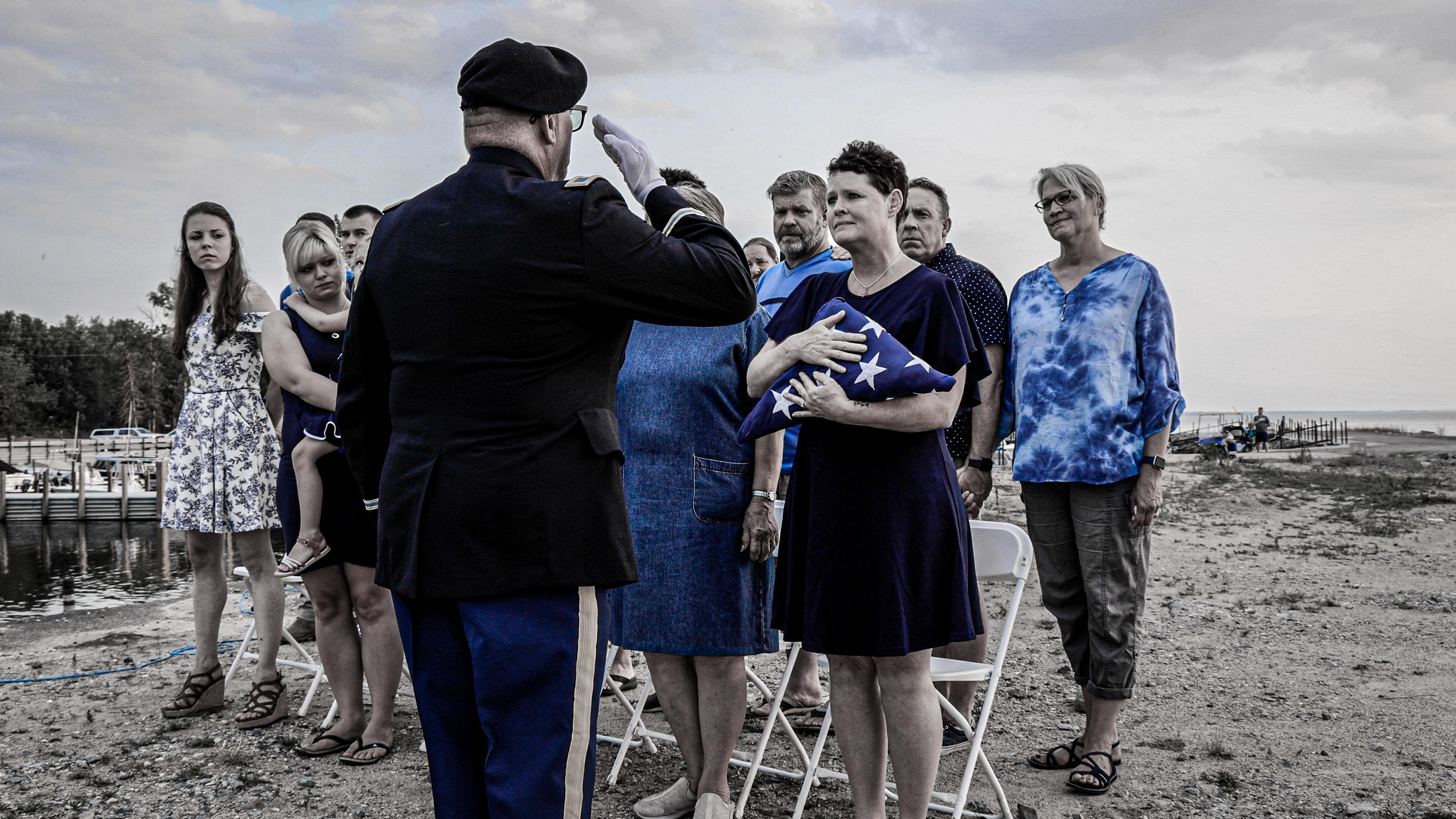 Samantha Bode, the late Mark Bode's wife being presented with a flag by Col. Ken DeGier (RET) after the memorial service at Lake of the Woods during an annual veterans gathering.