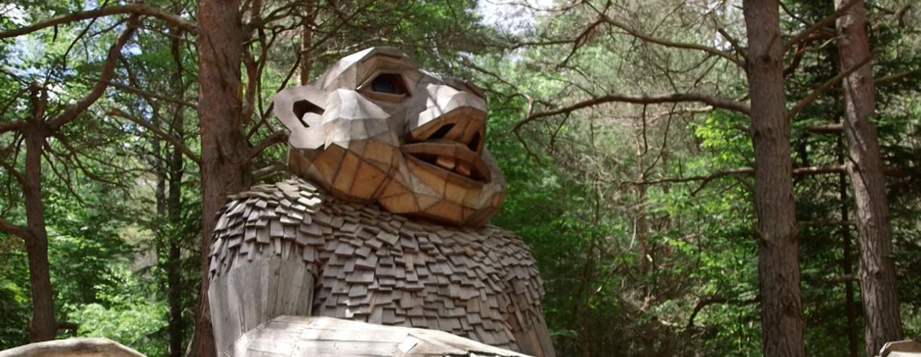 Giant wooden troll sculpture in the woods.
