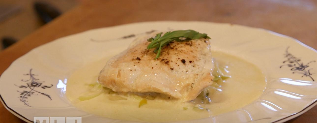 Steamed salmon piece on a plate with tarragon.