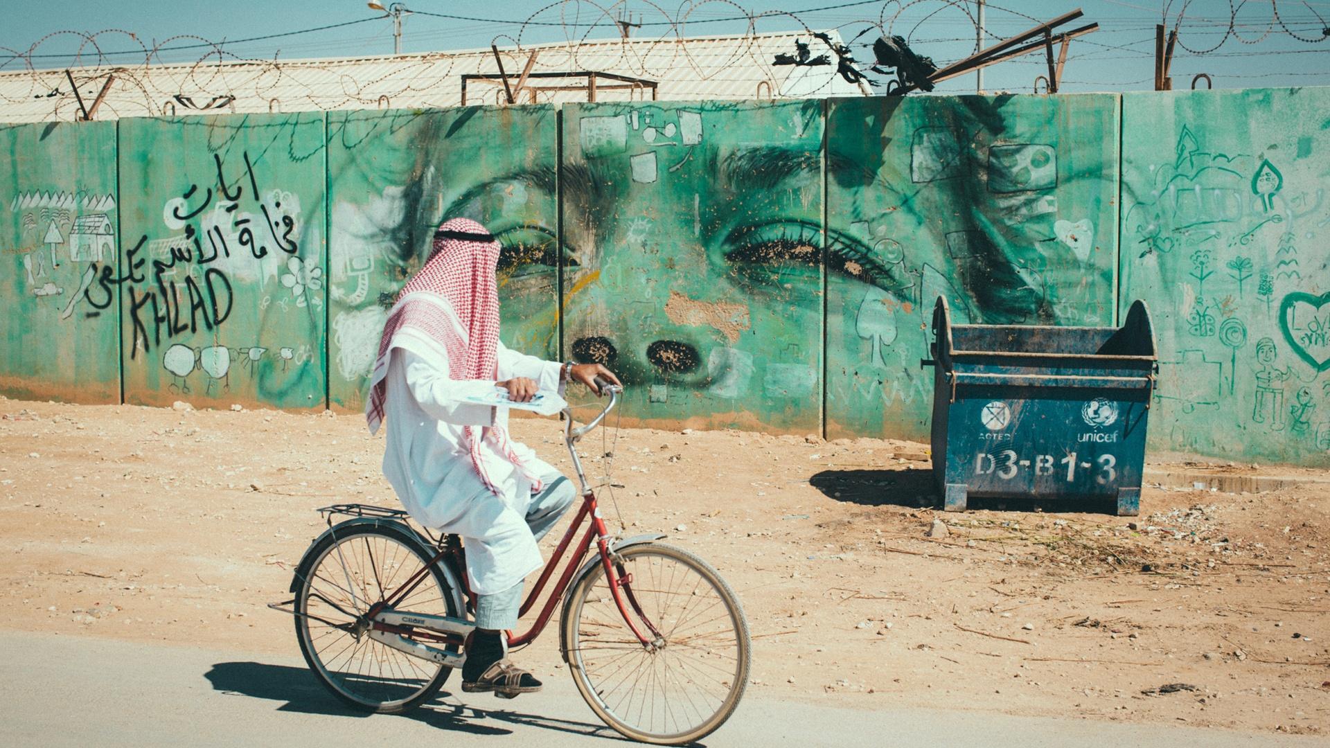 A cyclist, passes graffiti in Gaza, Palestinian Territory. In Gaza, the aquifer is overdrawn and water has been scarce for decades.