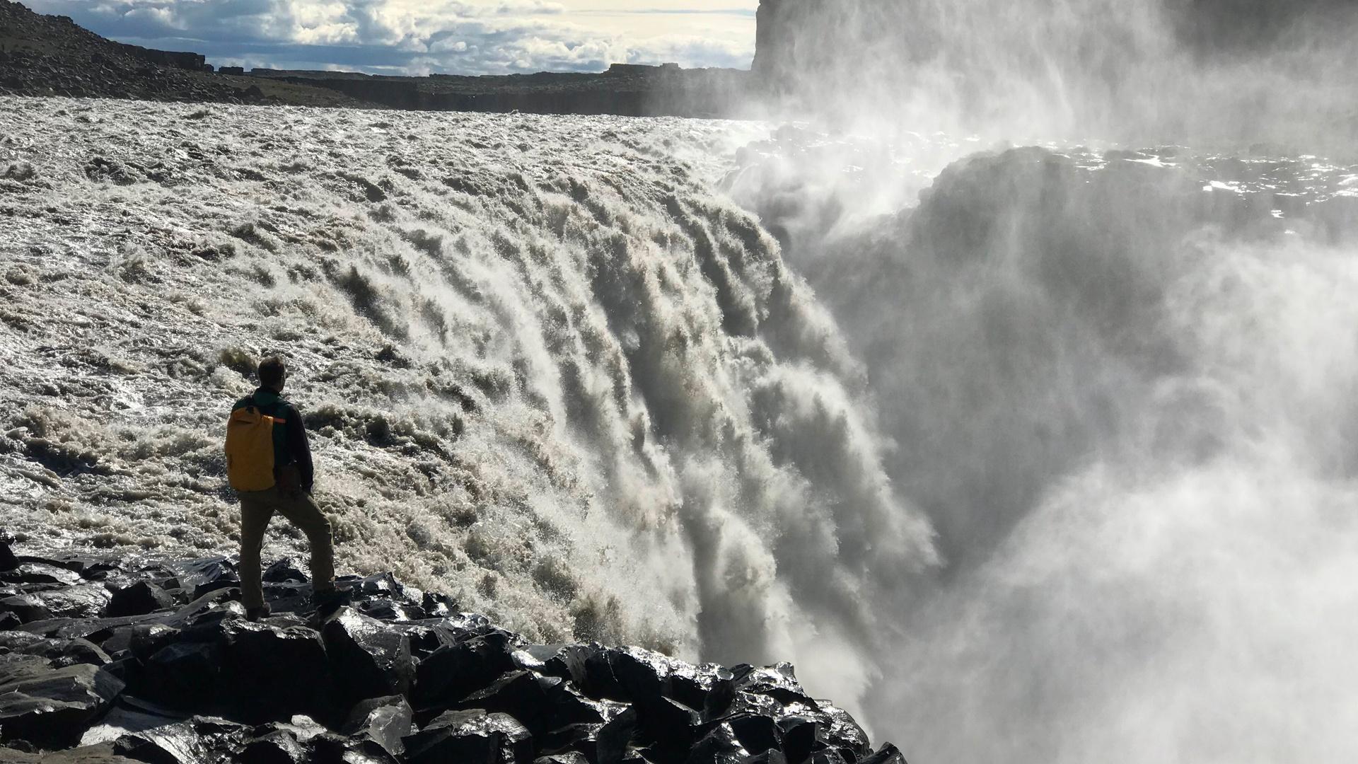 Stephen Mojzsi, geologist, stands at the top of a waterfall in Isua, Greenland.
