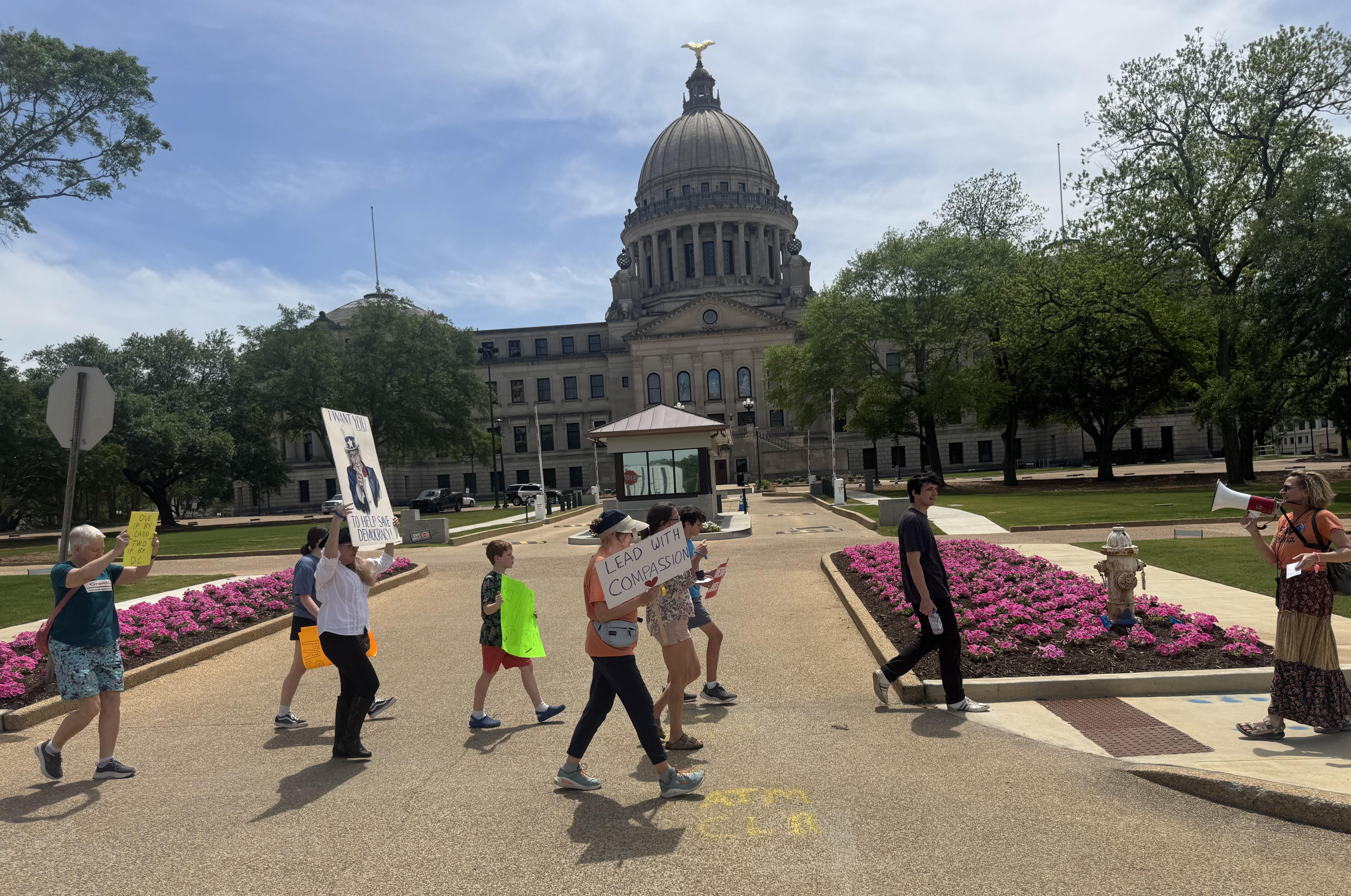 A line of protesters is seen holding signs in front of Mississippi's state capitol building.