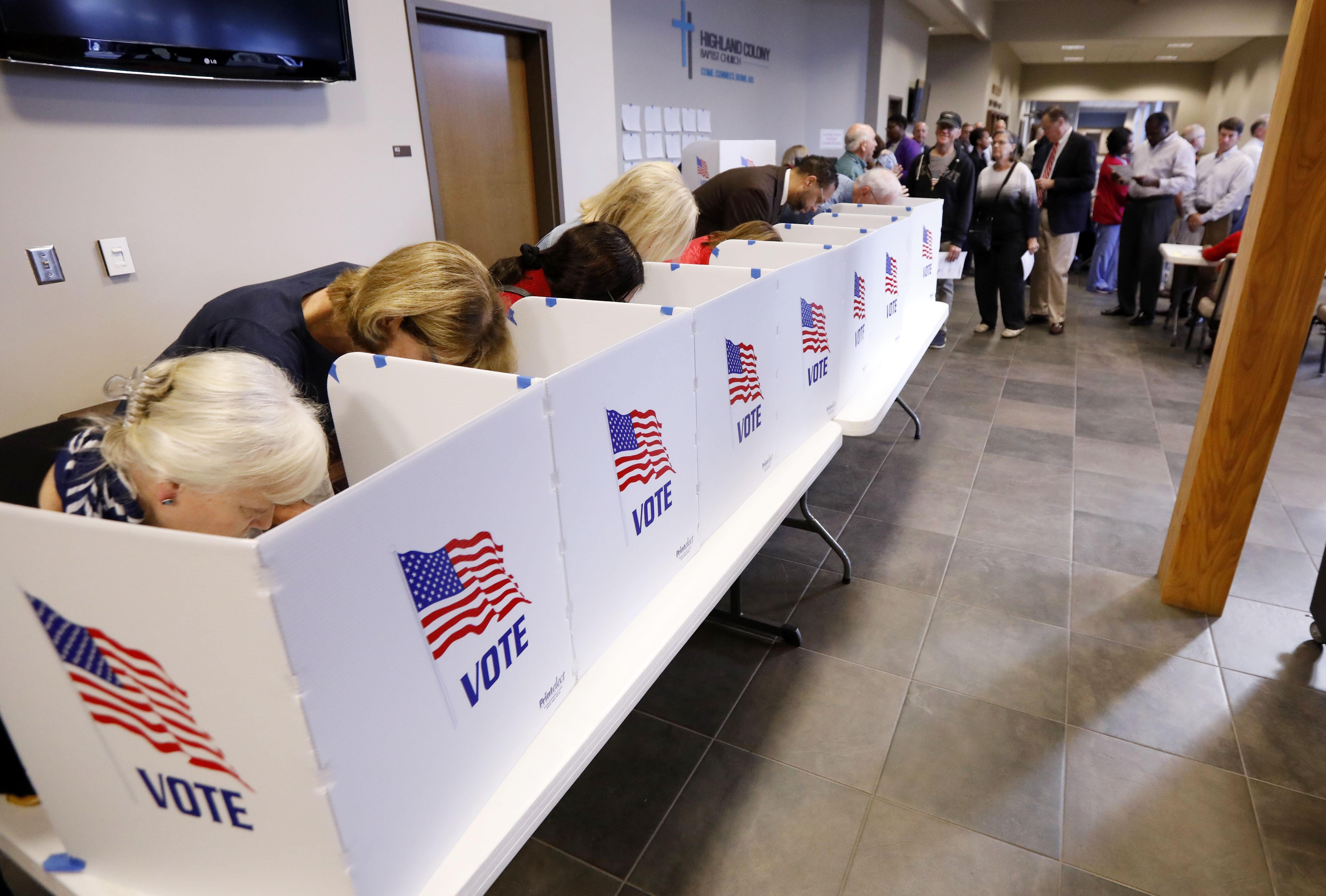 A growing line of voters, right, wait as others fill out their paper ballots in privacy voting booths, Tuesday, Nov. 6, 2018, in Ridgeland, Miss. Voters have a number of races to consider, including judiciary and federal offices and some local issues.