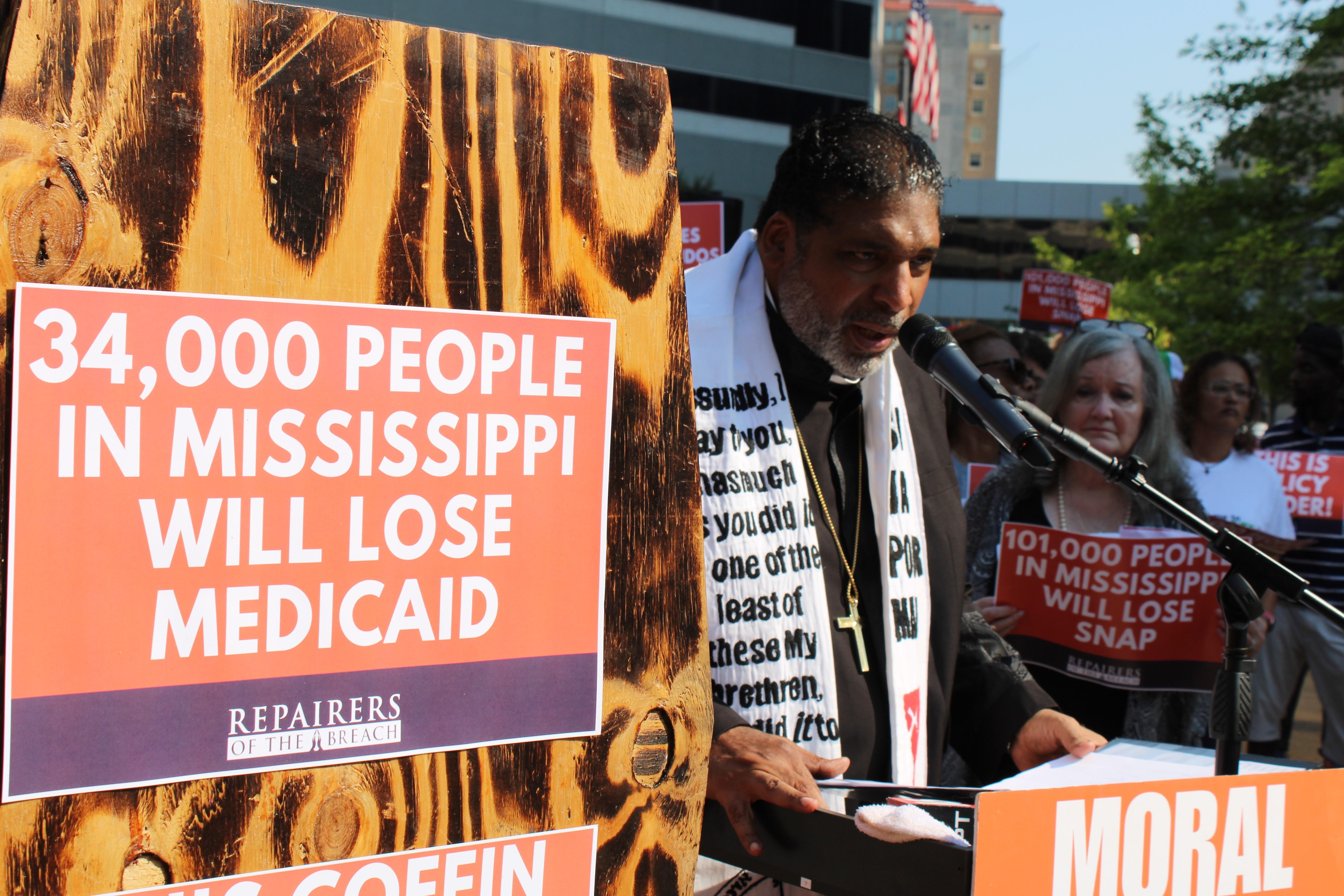 A reverend speaks into a microphone in front of activists.