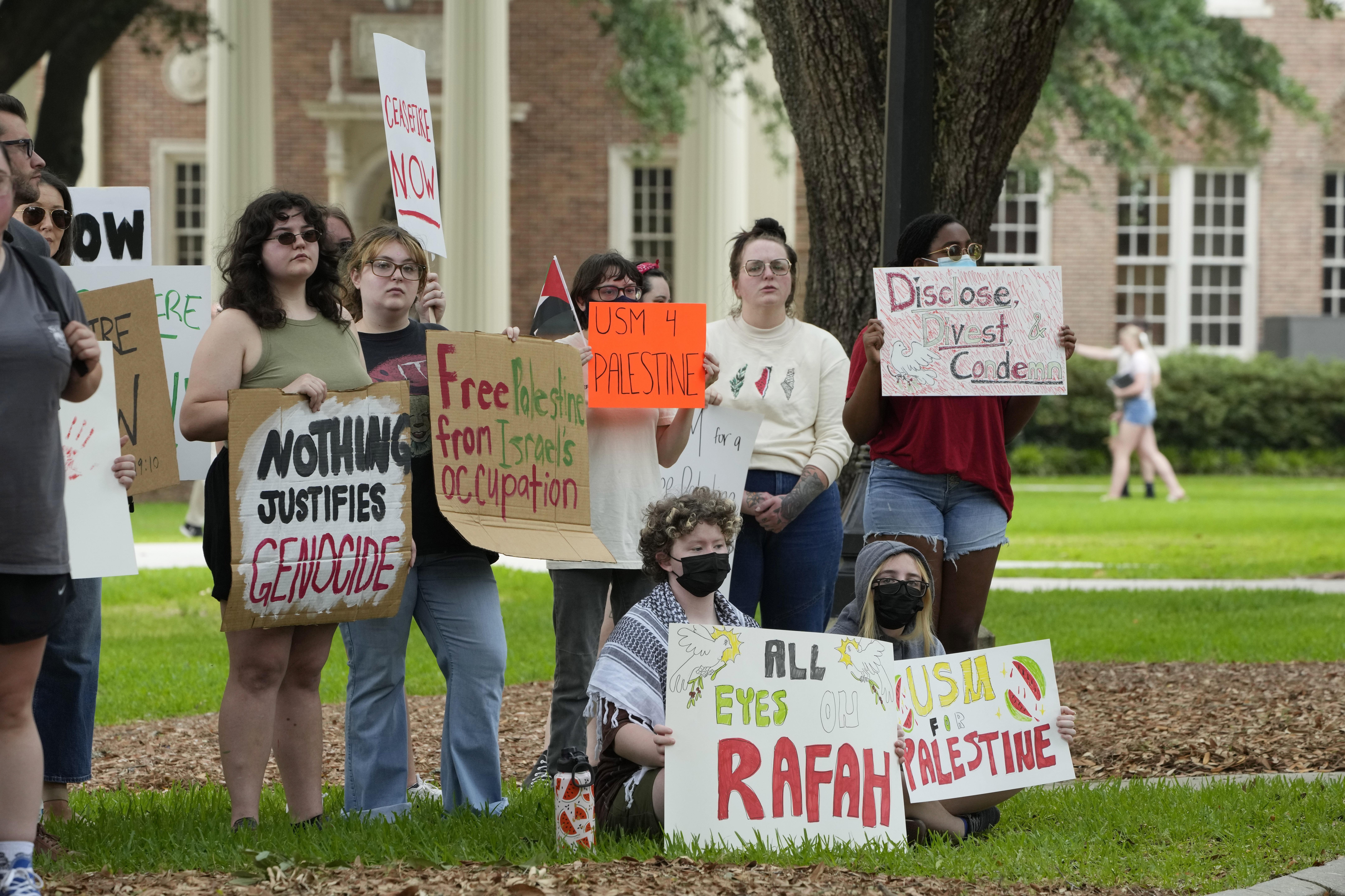 A group of young adults holds signs protesting the war in Gaza