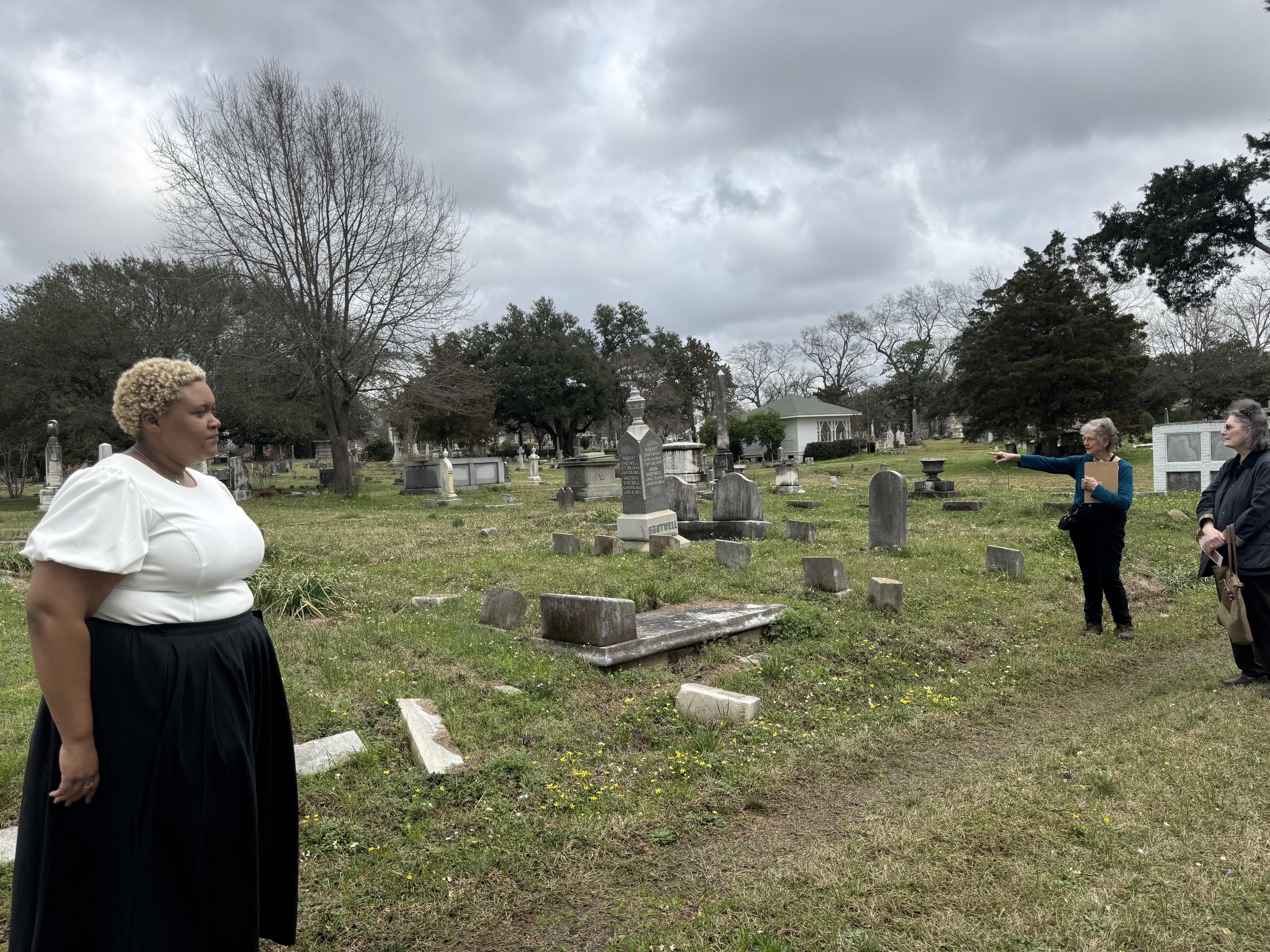 A young woman stands in front of people in a cemetery