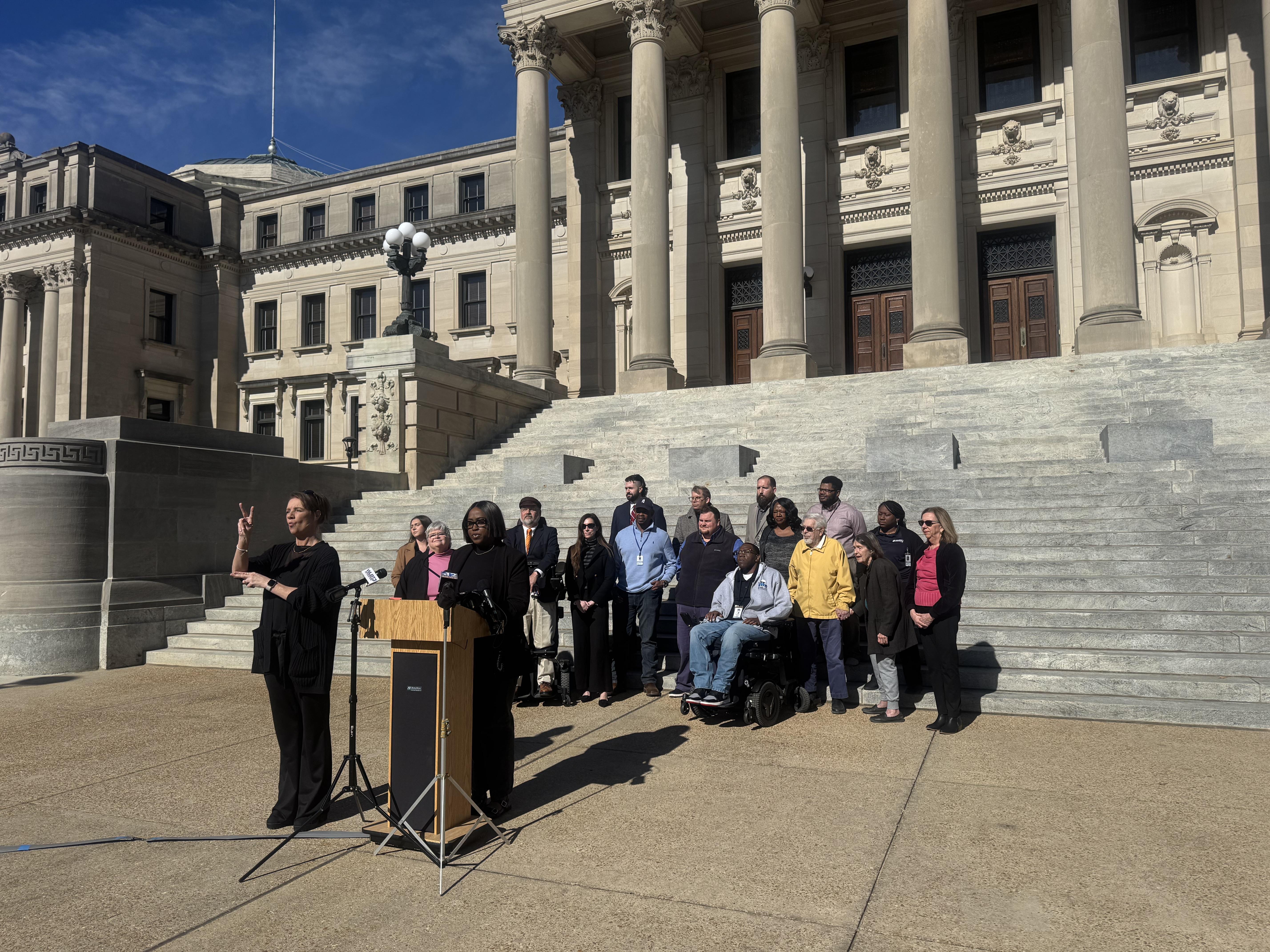 A group of people stand in front of the Mississippi state capital.