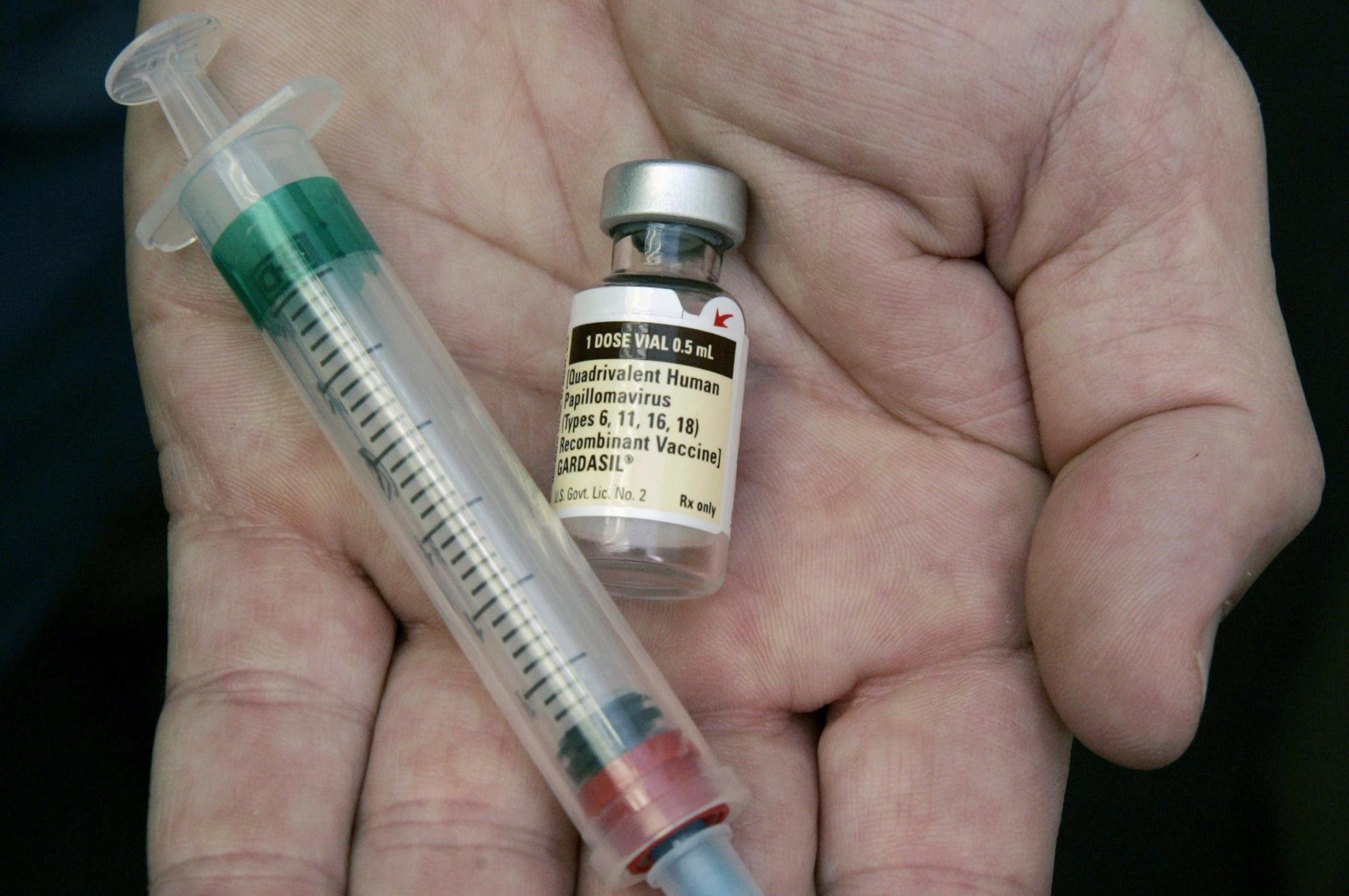 A doctor holds a vial containing a vaccine.