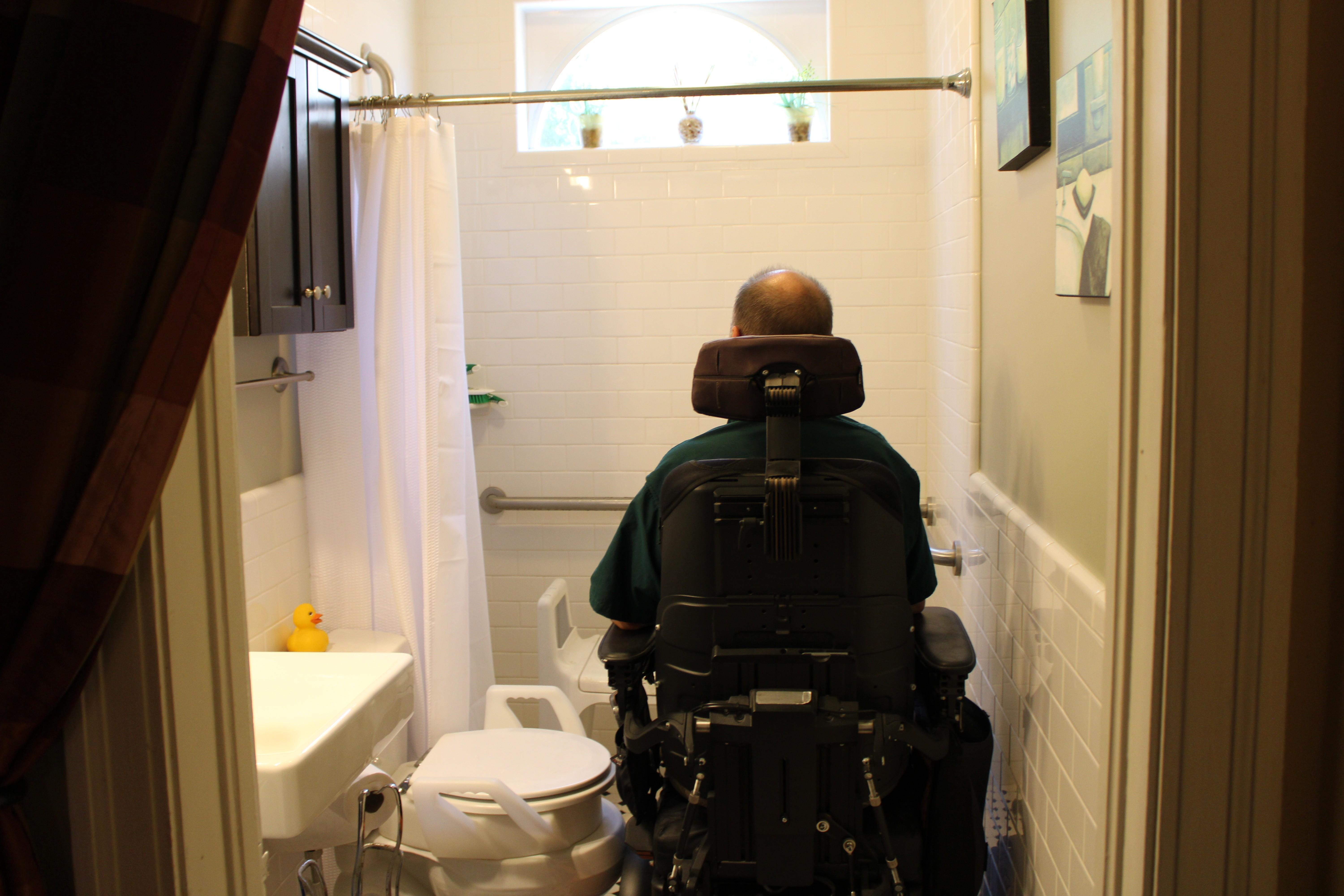 A man using an electric wheelchair demonstrates how narrow his bathroom is.