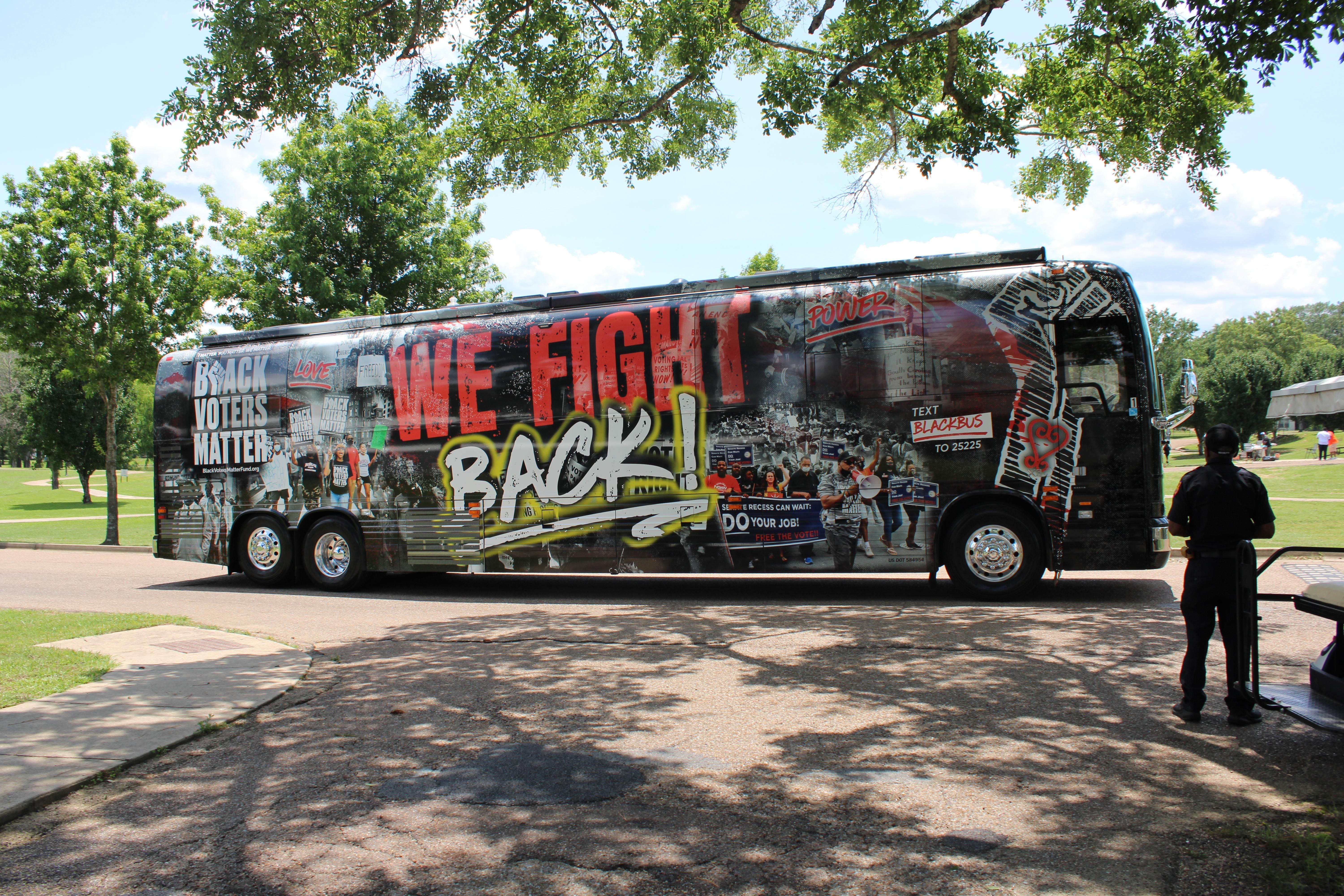A bus with images of Black protesters pasted on it drives through a college campus.
