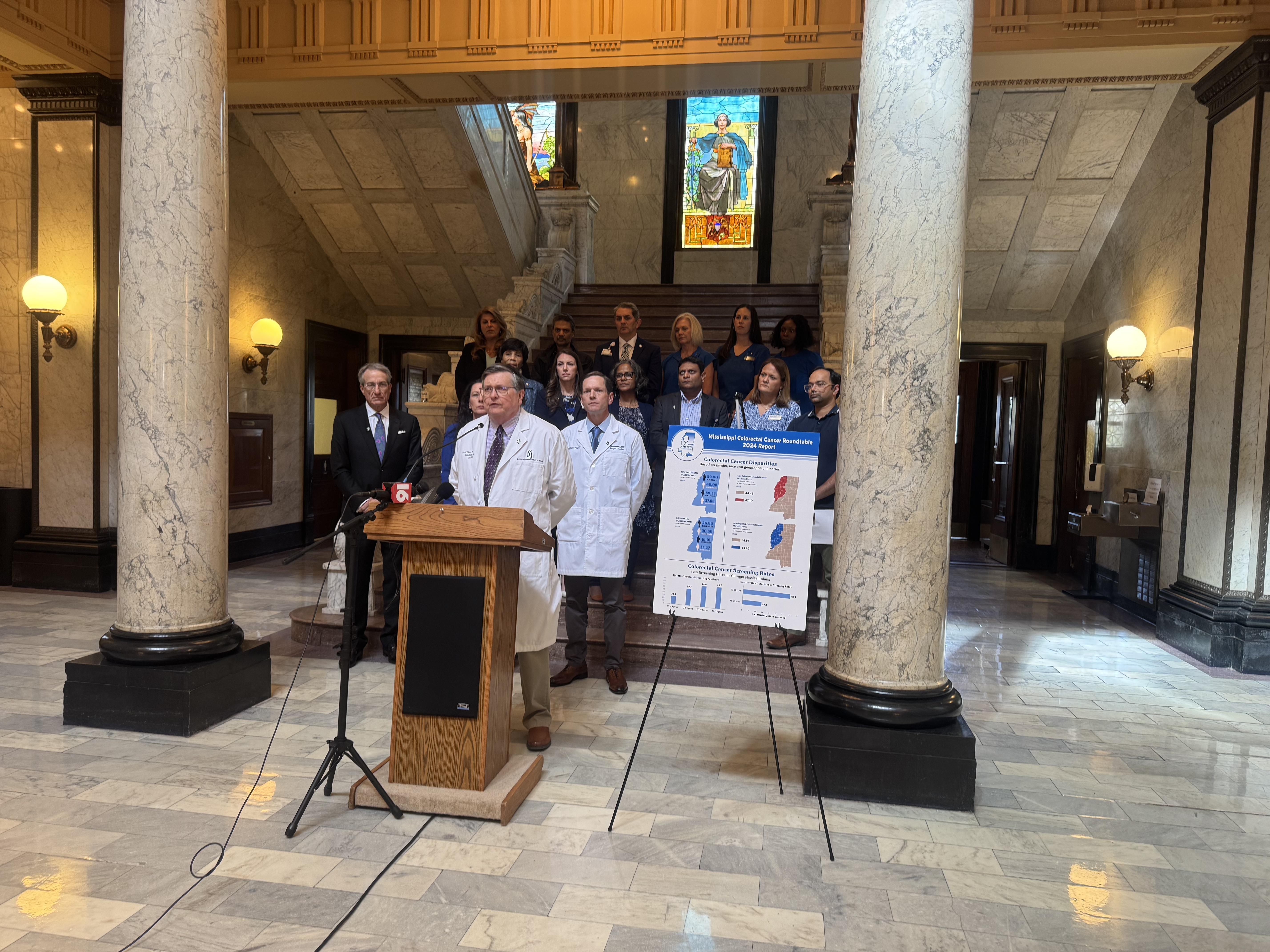 A doctor stands behind a podium at a press conference.