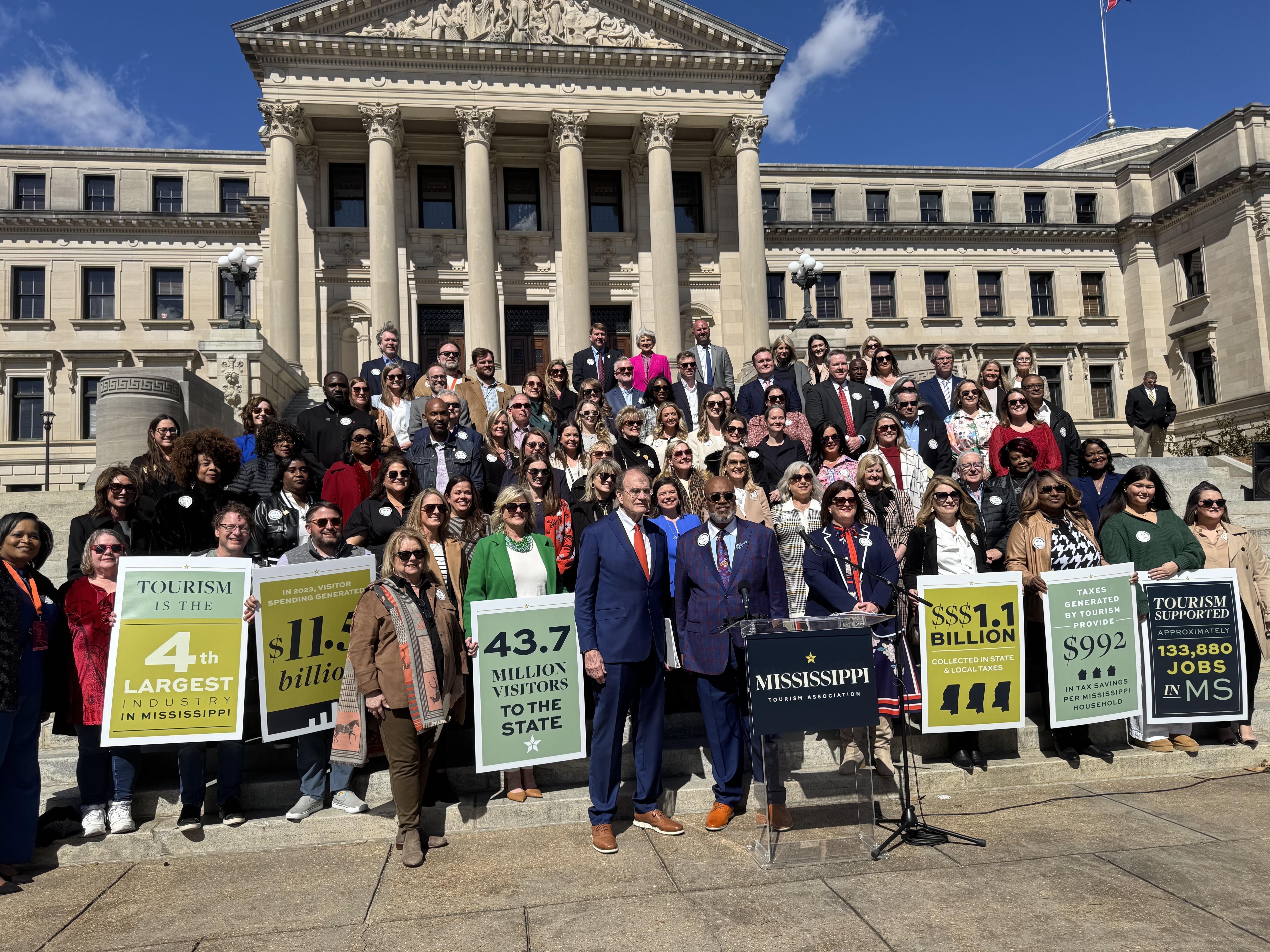 A large group of people stands in front of the Mississippi state capitol