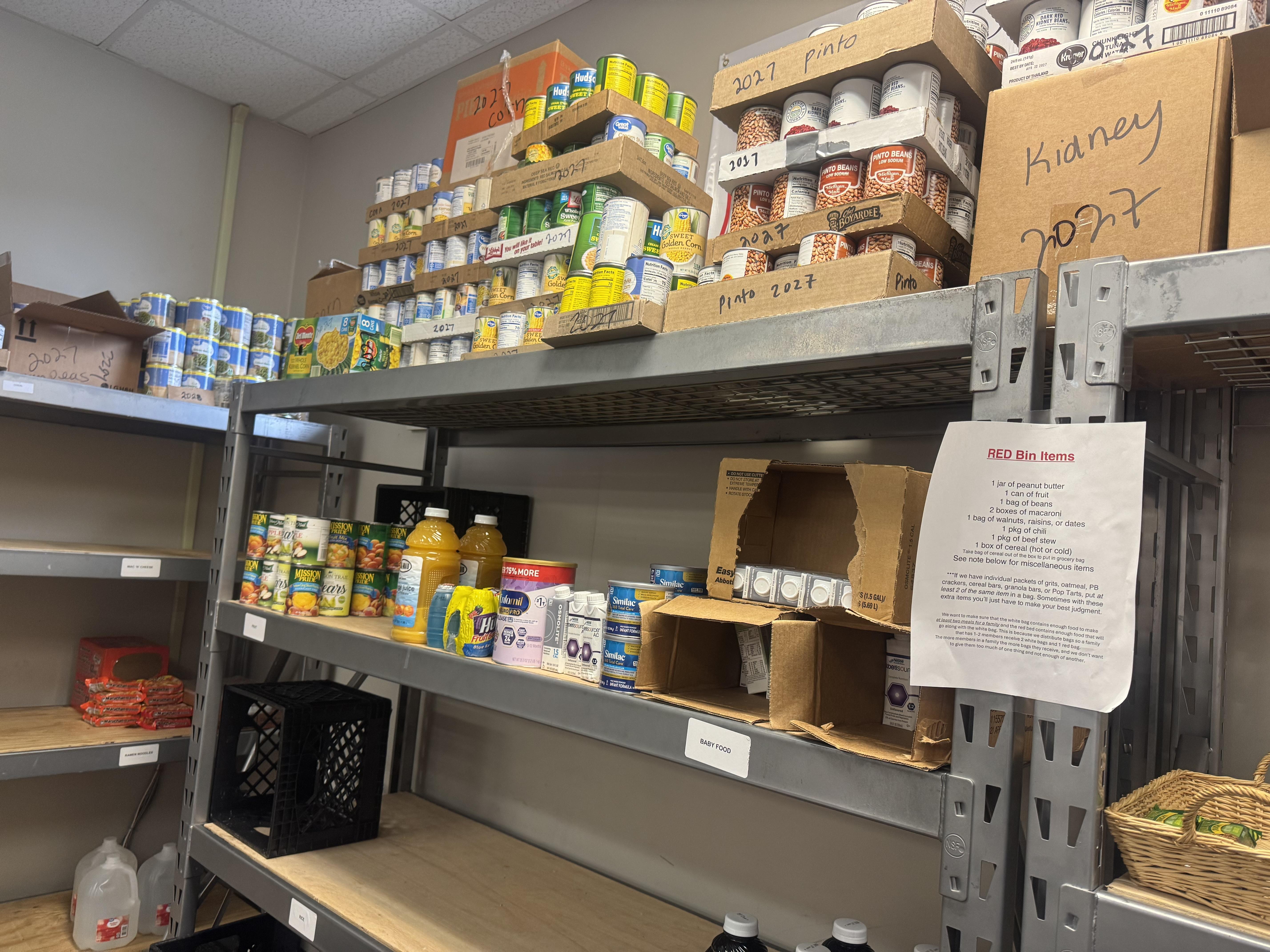 A shelf has cans of food, baby formula and empty space.