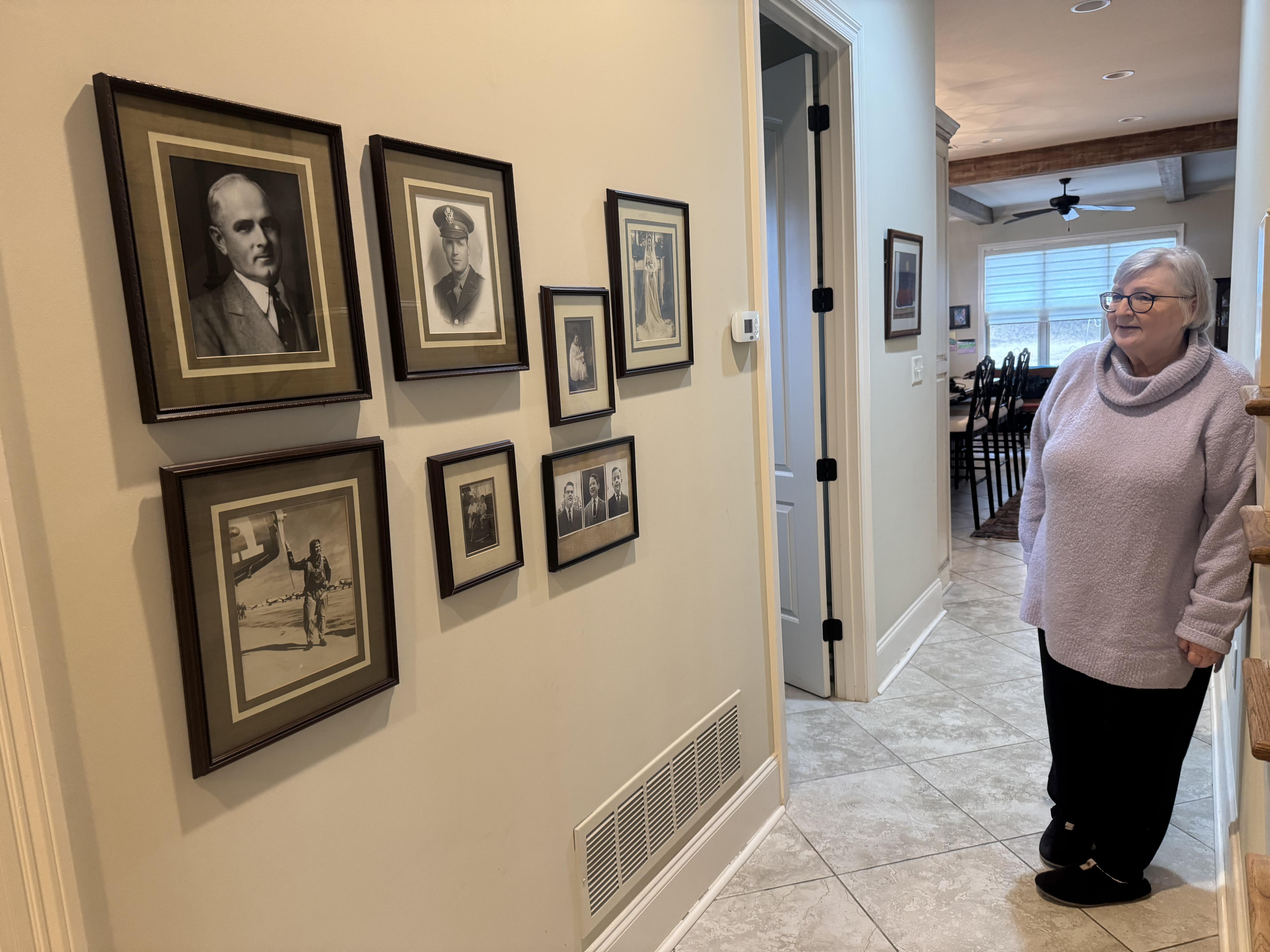 A woman looks at the black and white photographs of ancestors.