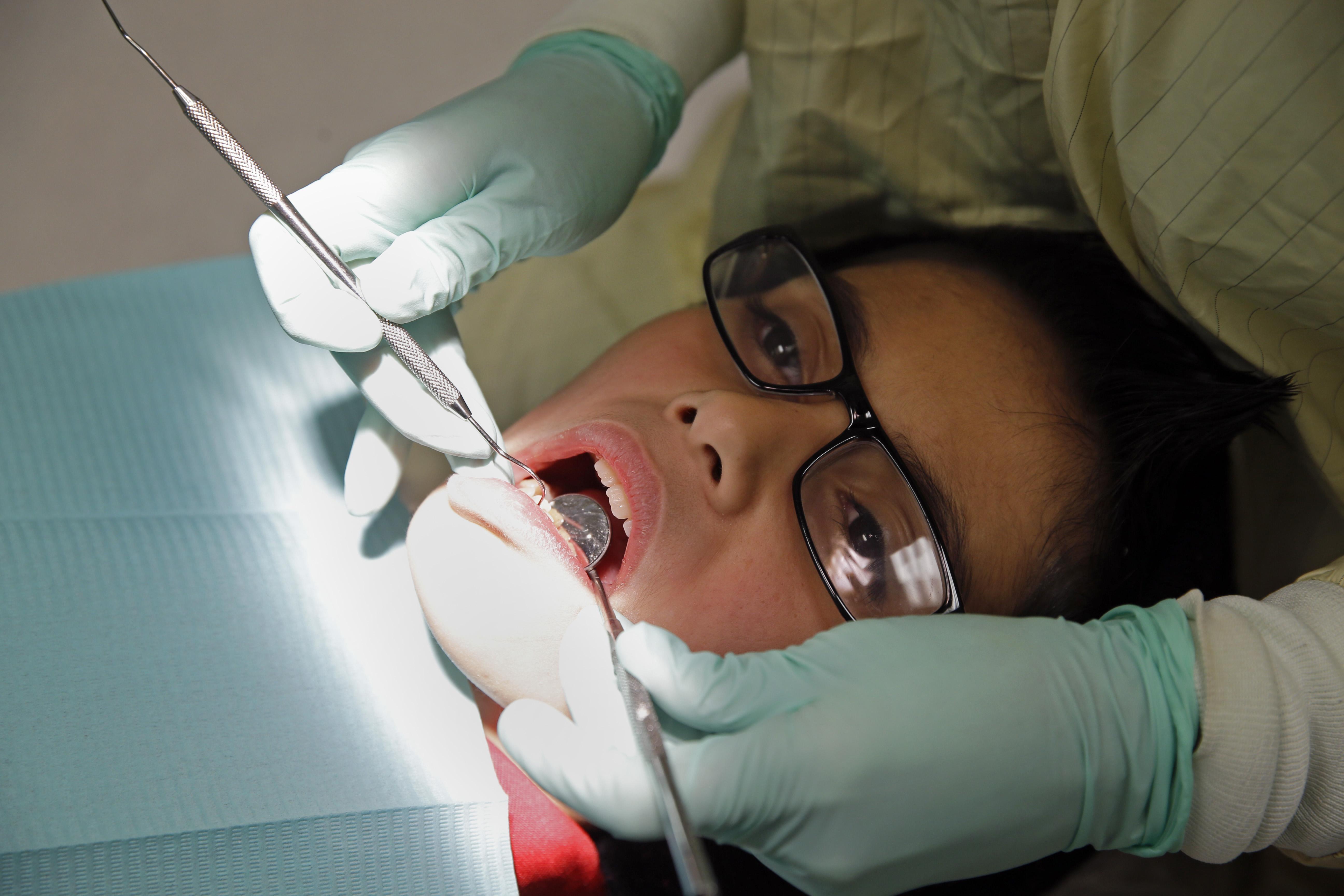 A dentist uses tools to inspect a child's teeth.