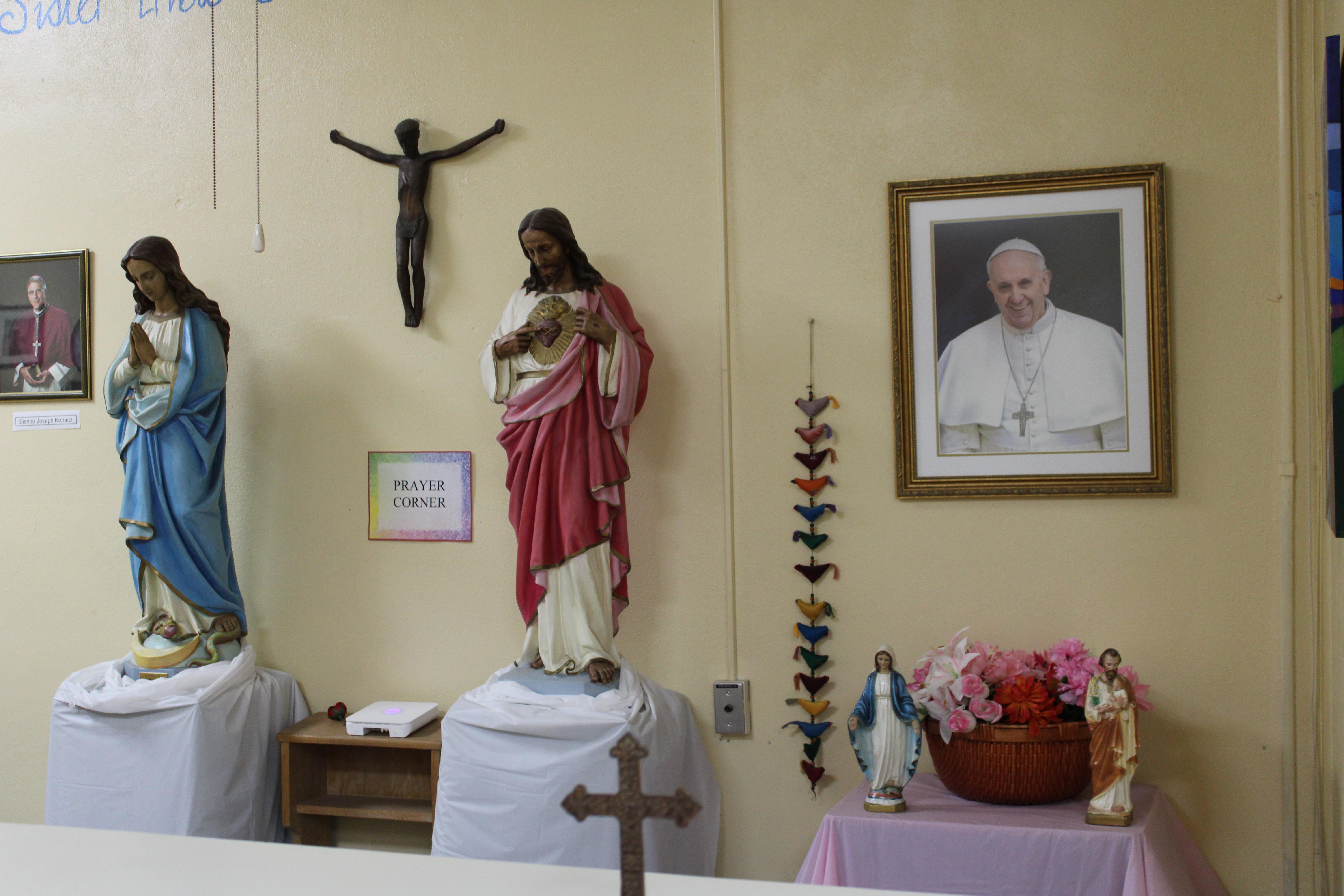 Statues representing the Virgin Mary and Jesus Christ stand beside a framed portrait of the late Pope Francis.