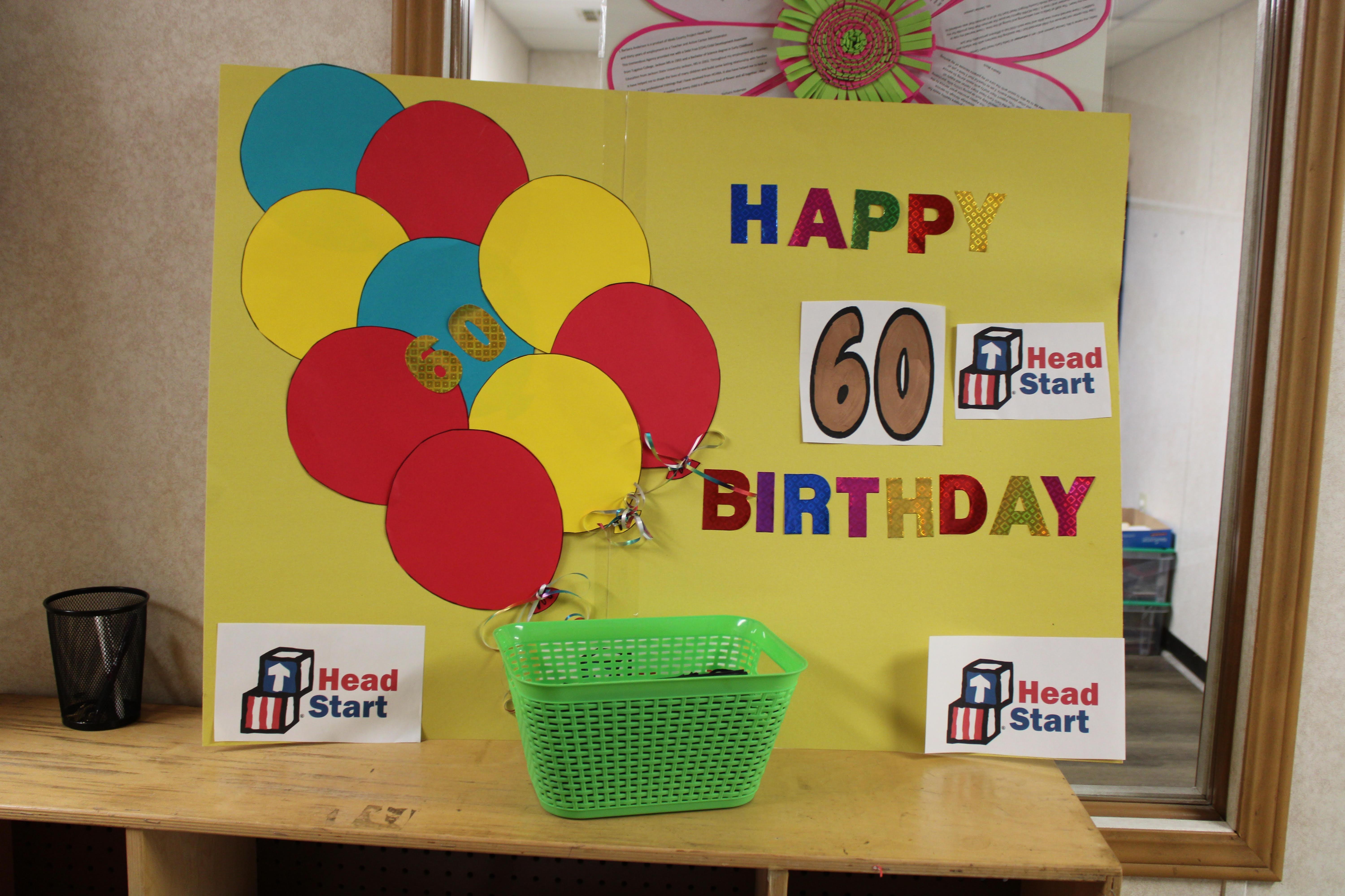 A yellow poster with red and yellow balloons and the Head Start logo says 'Happy sixtieth birthday' to the program.