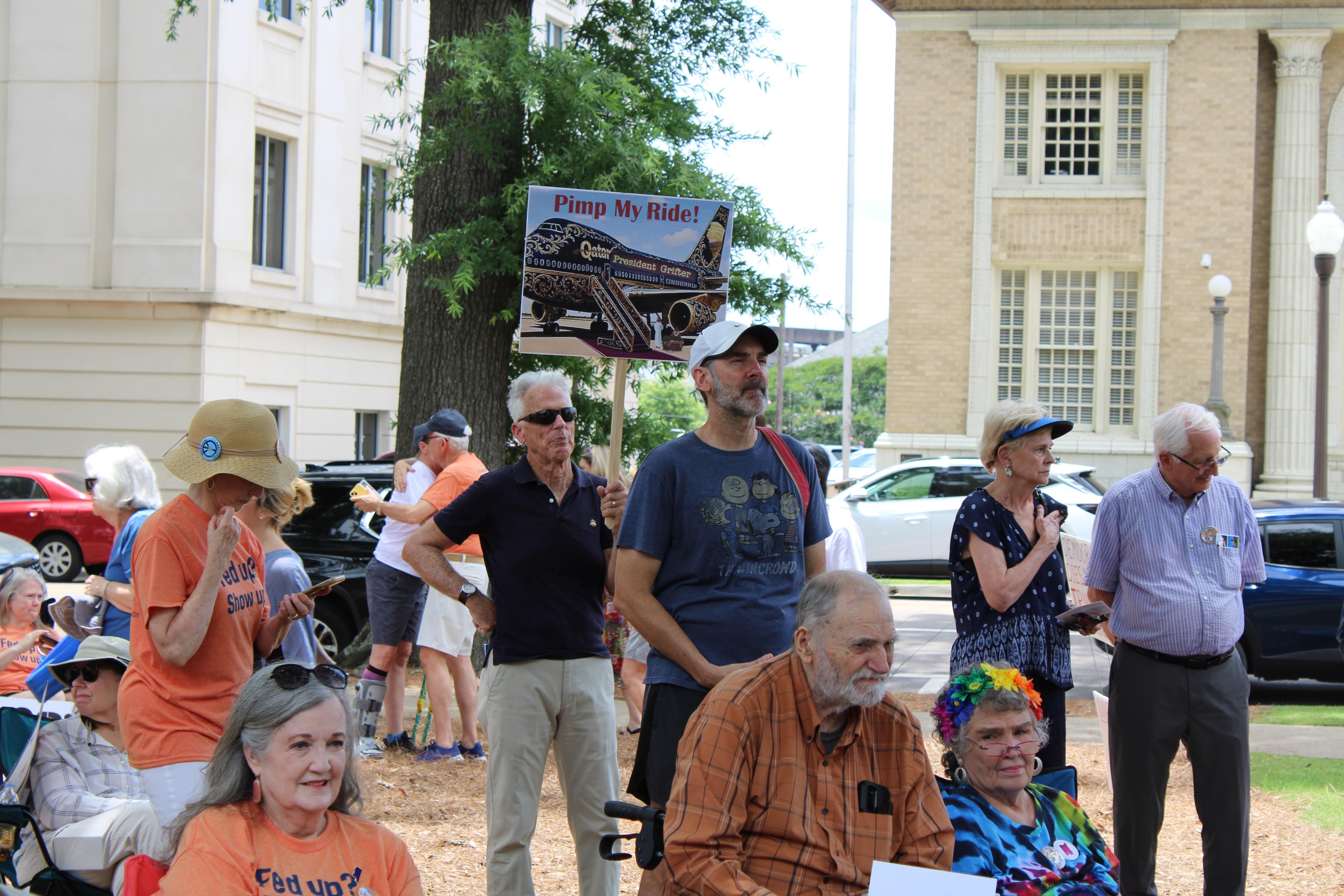 A group of protesters, one carrying a sign, look on.