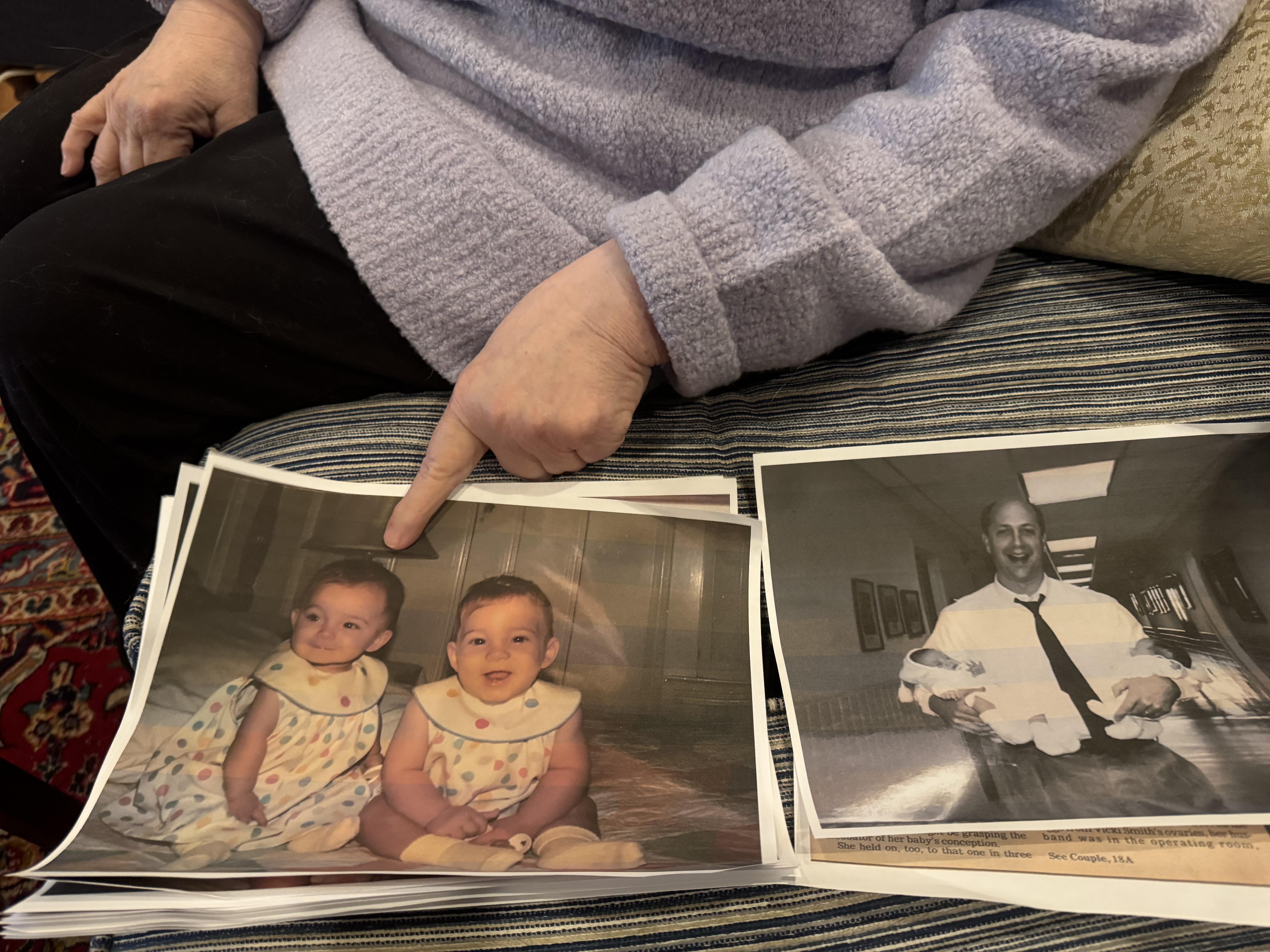 A mother points to a photo of twin baby girls while in another black and white photo, a proud doctor holds the twins as newborns.