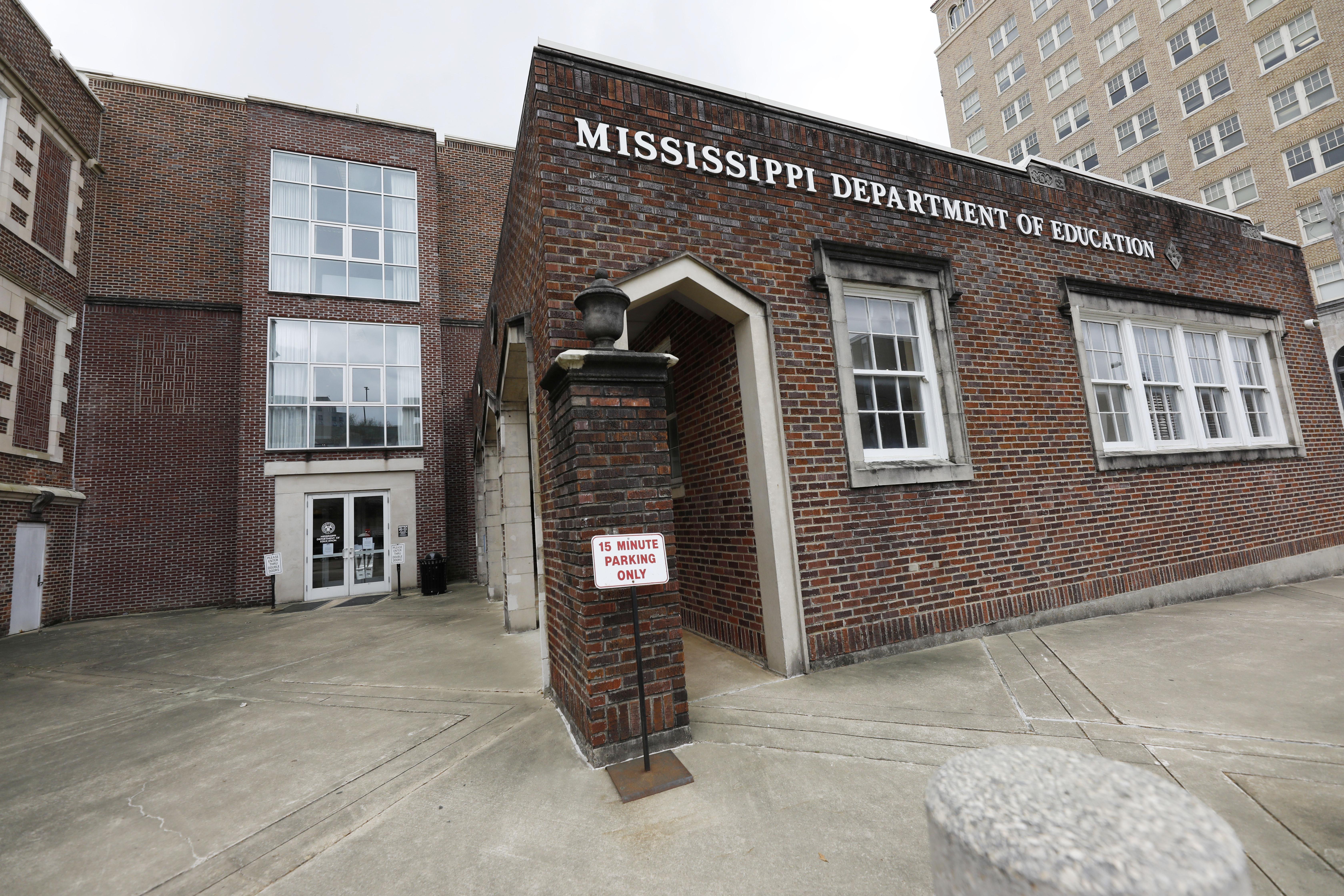 The brick exterior of a former school is seen with a 15-minute parking sign.
