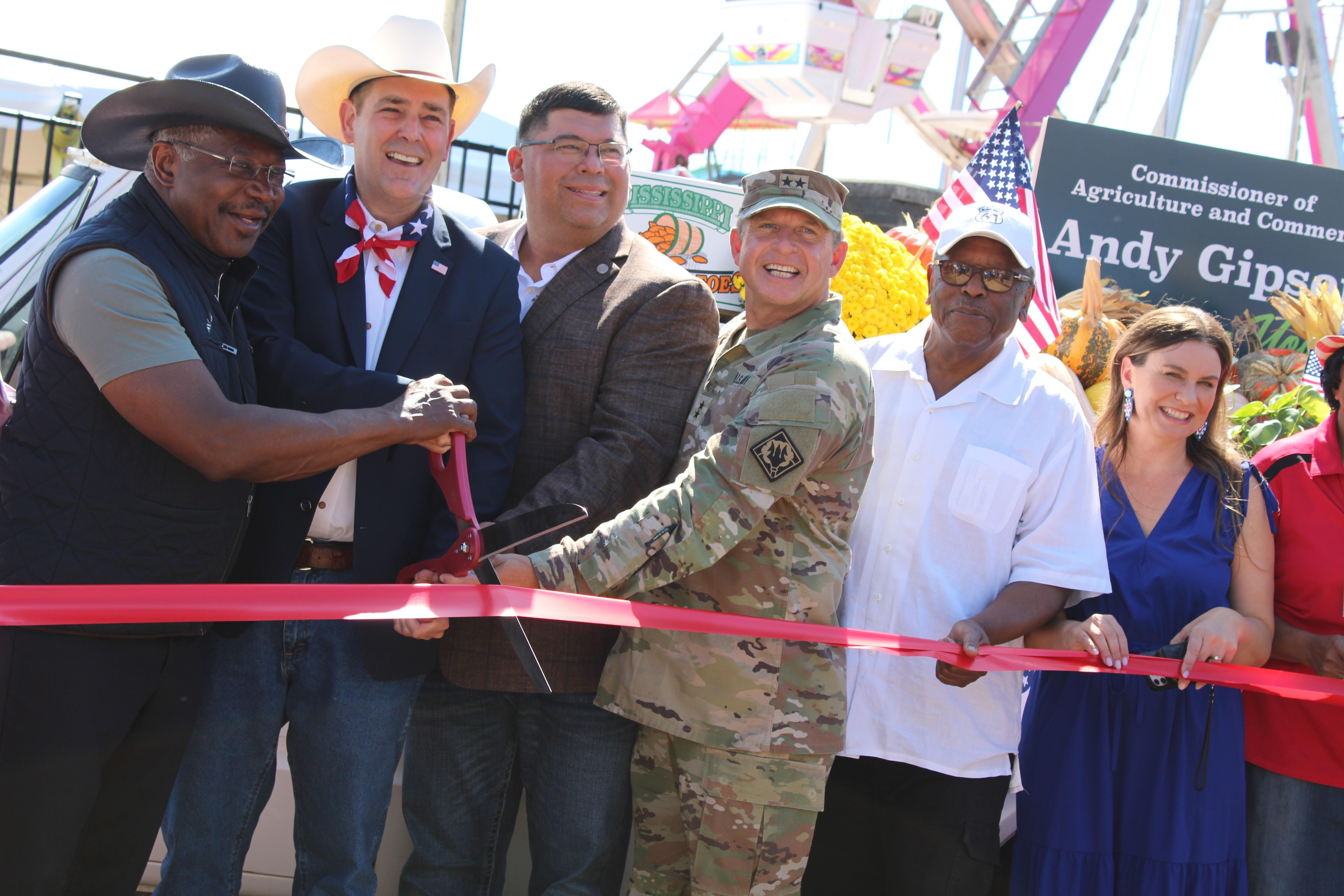 Several people cut a red ribbon with excitement