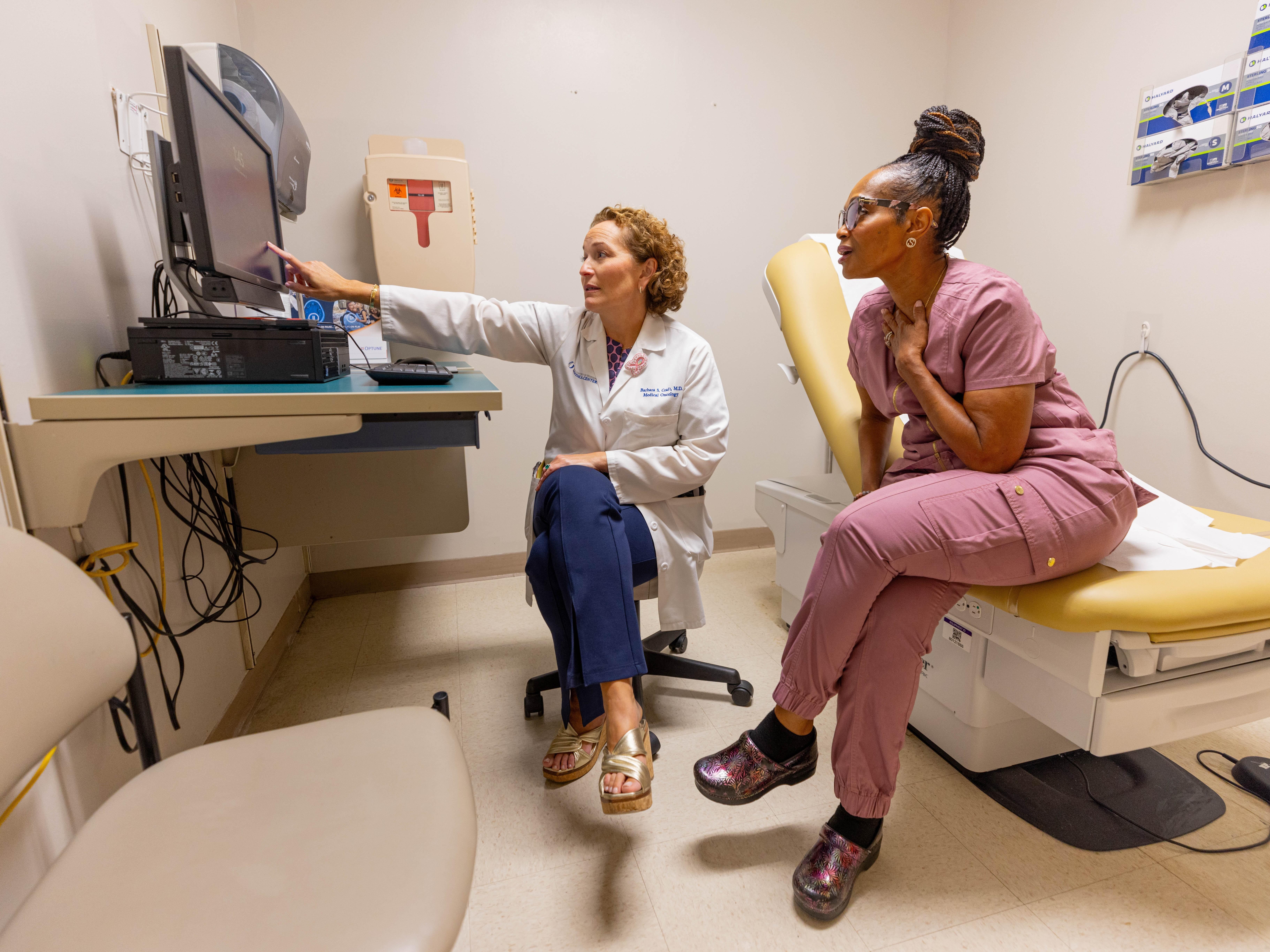 A woman listens to a doctor, with her hand to her chest, 