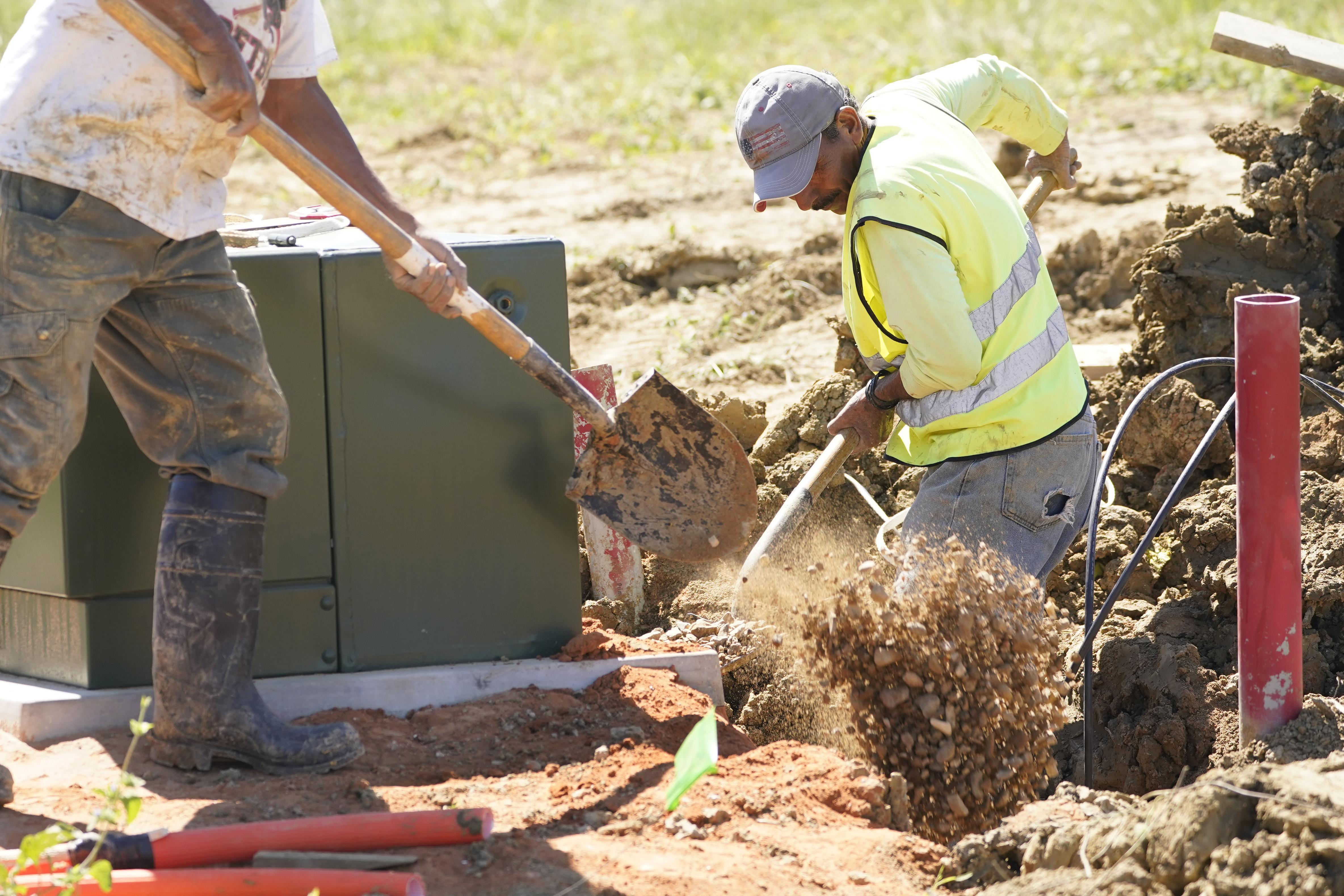 Construction workers lift dirt with shovels
