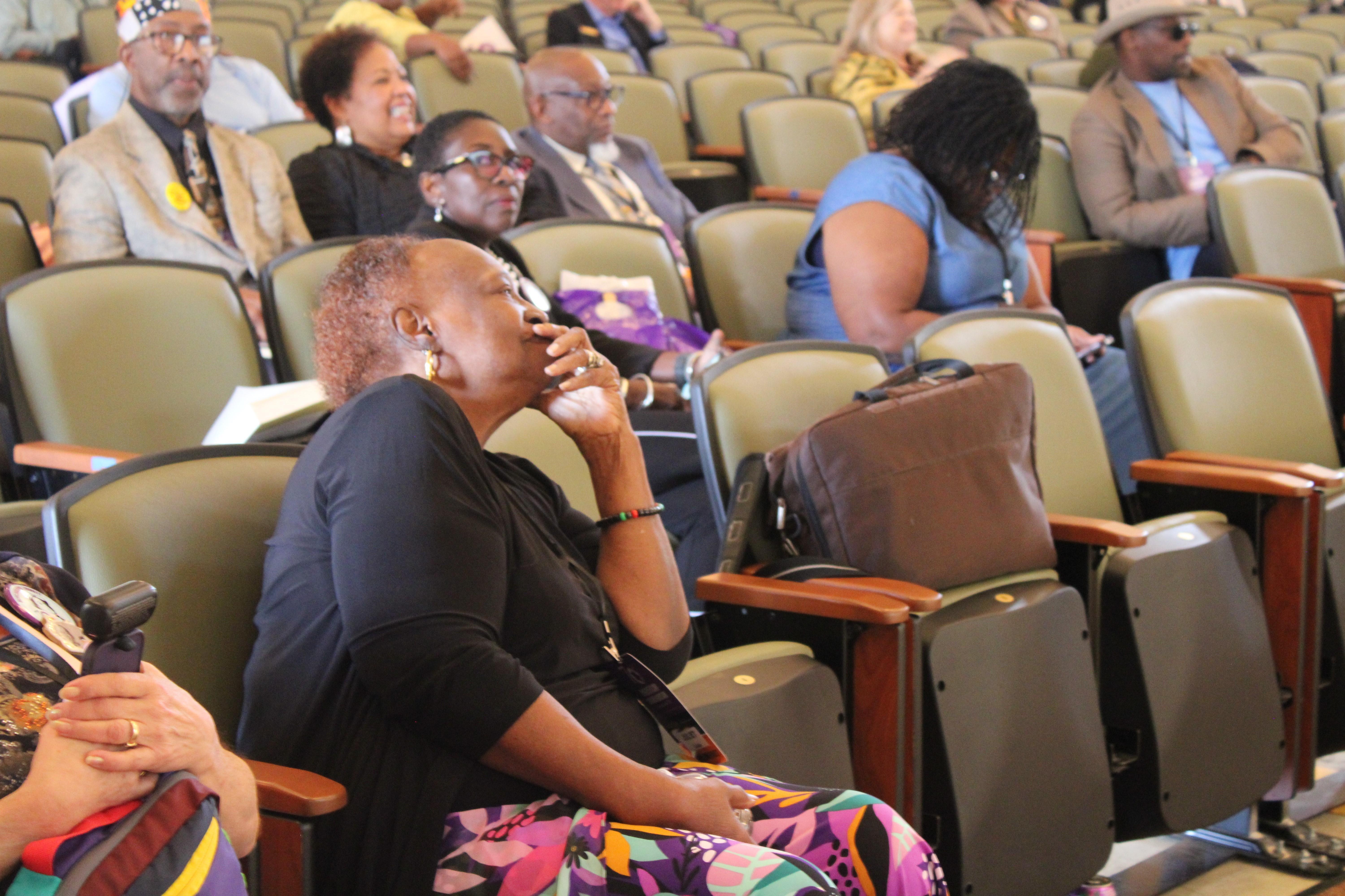 A woman listens to a panel, appearing to be in deep thought.