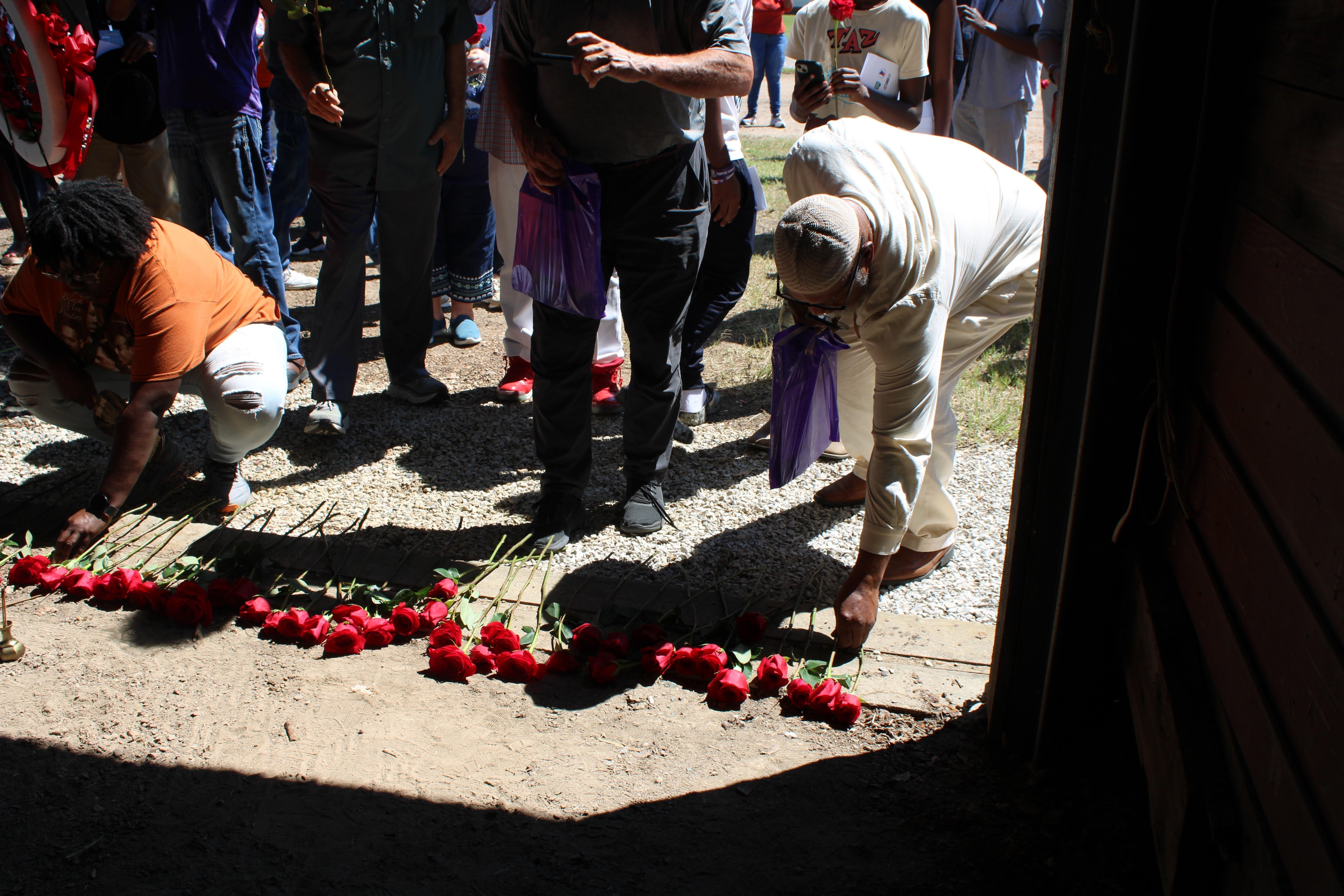 People place roses at the entrance of a historic building.