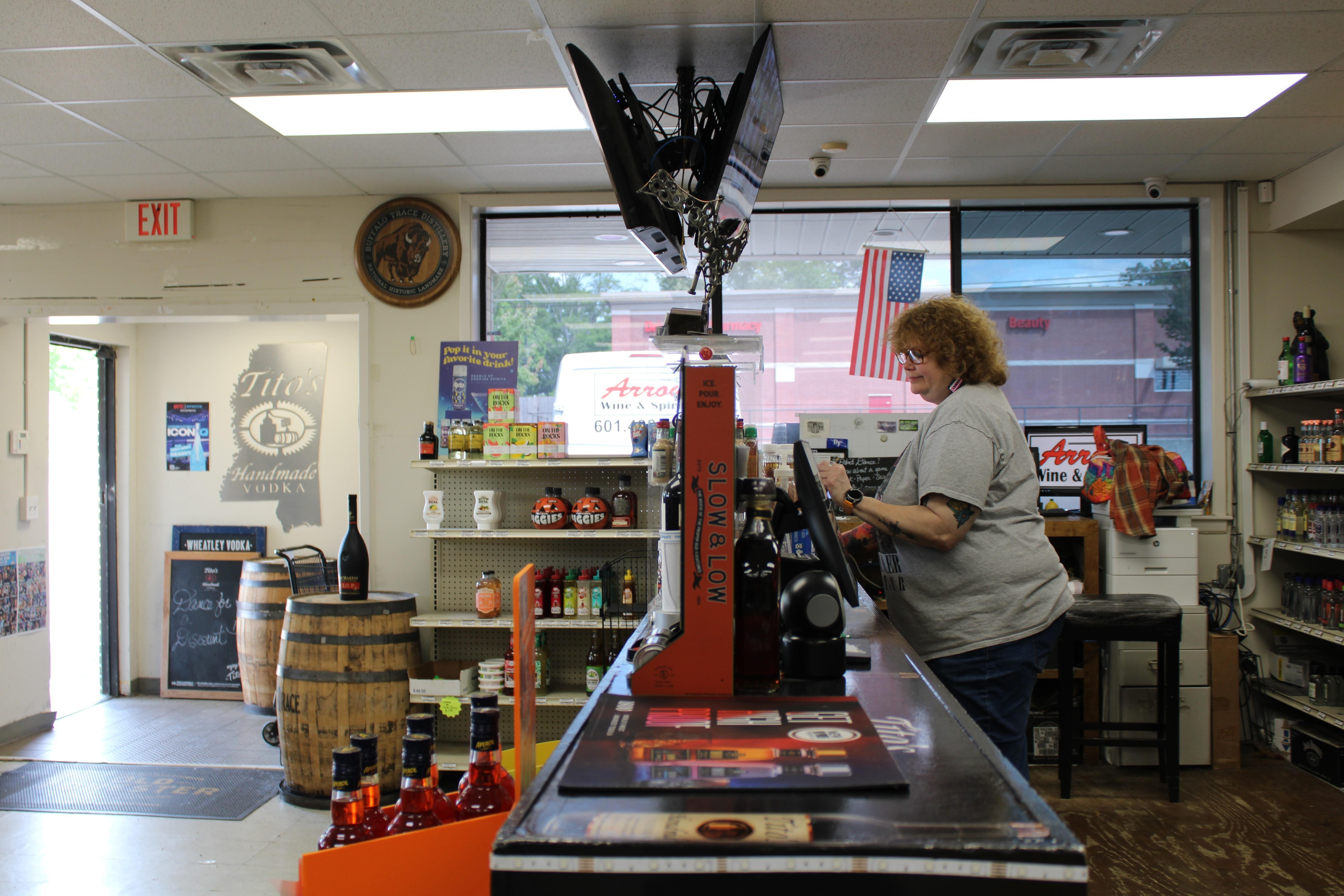 Arrow Wine and Spirits manager Shaun Blakeney waits for customers at the store's register.
