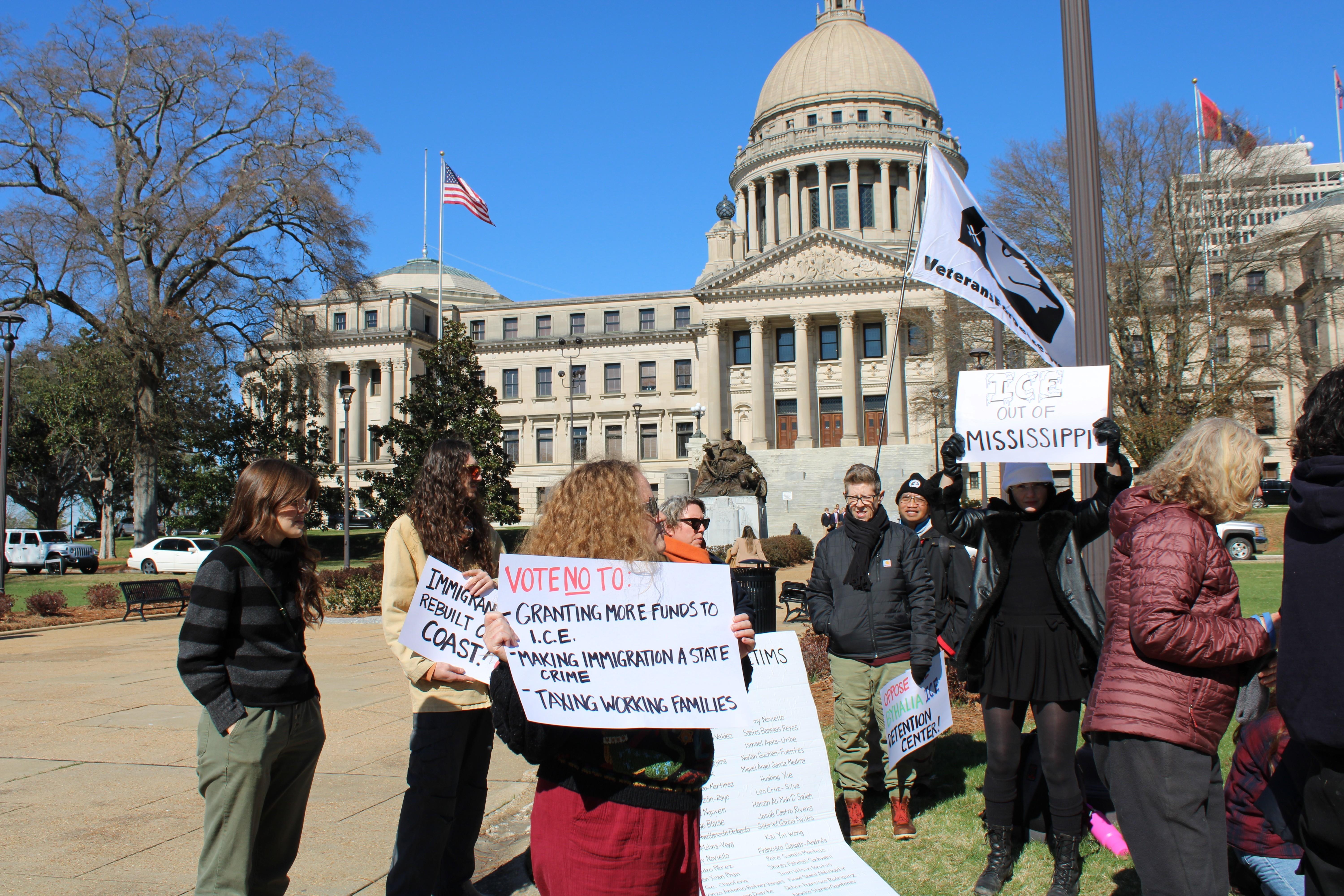 Protesters hold signs denouncing ICE enforcement outside of the Mississippi state capitol building. 