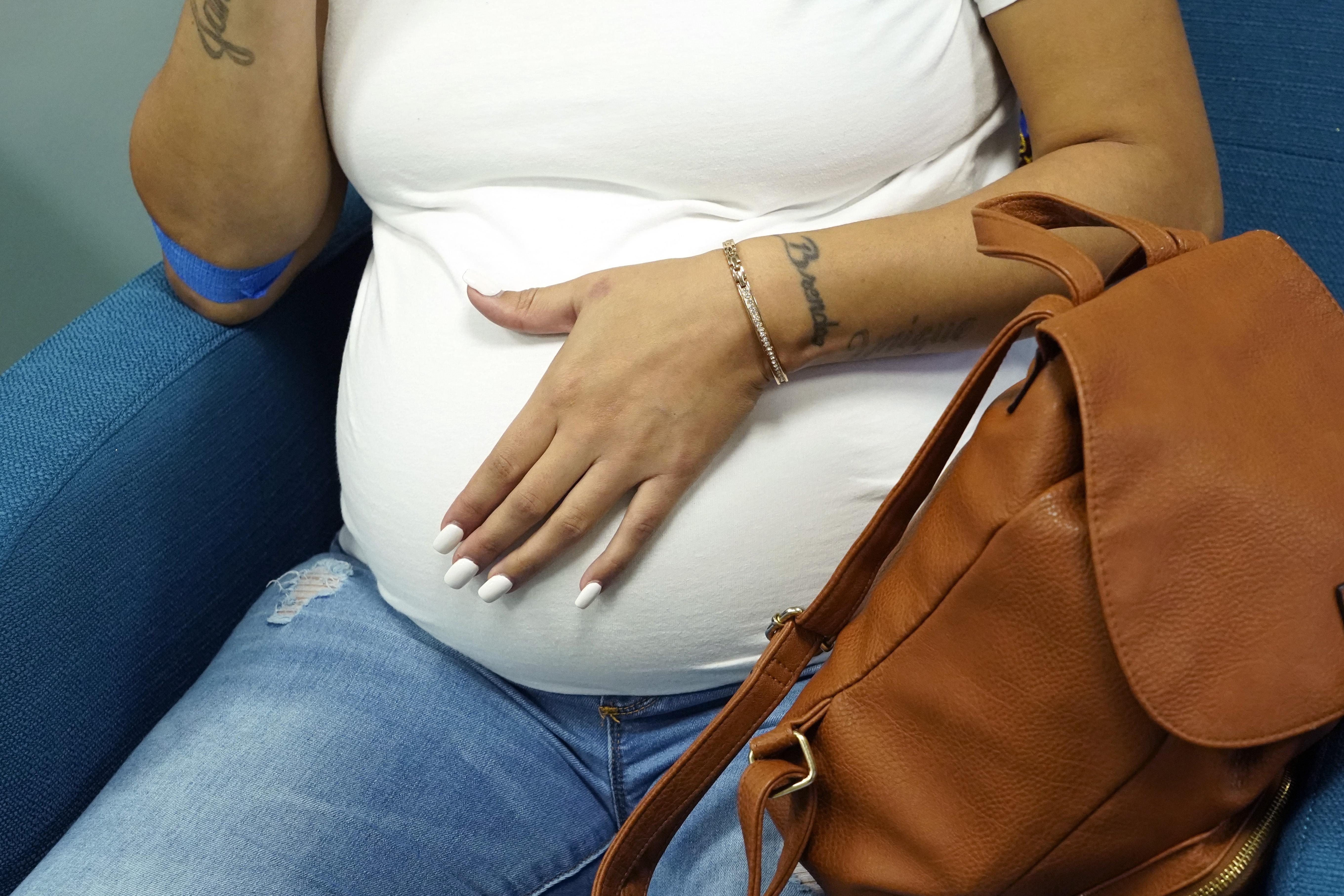Miracle Allen rubs her stomach as she relaxes before meeting with the midwife at Sisters in Birth, a Jackson, Miss., clinic that serves pregnant women, Dec. 17, 2021.
