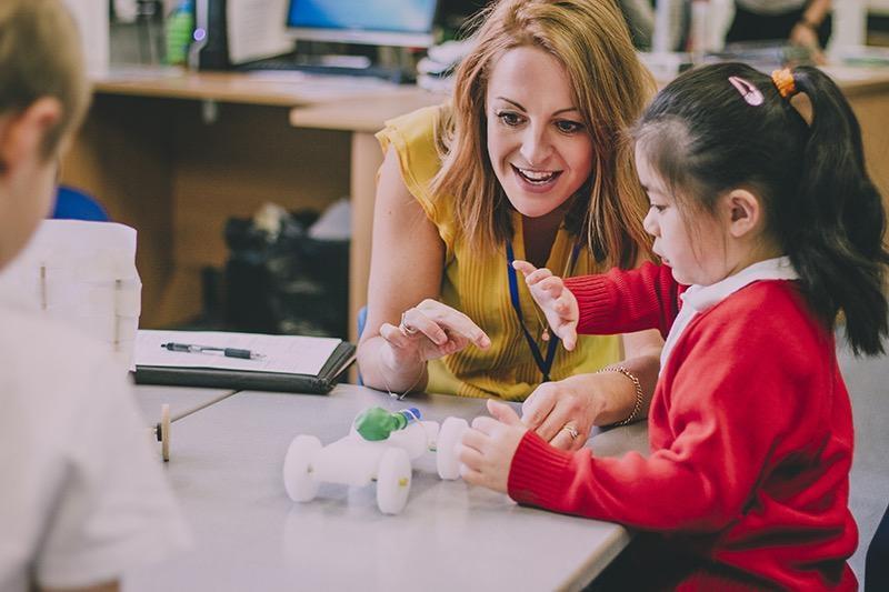 Teacher working with student on toy automobile