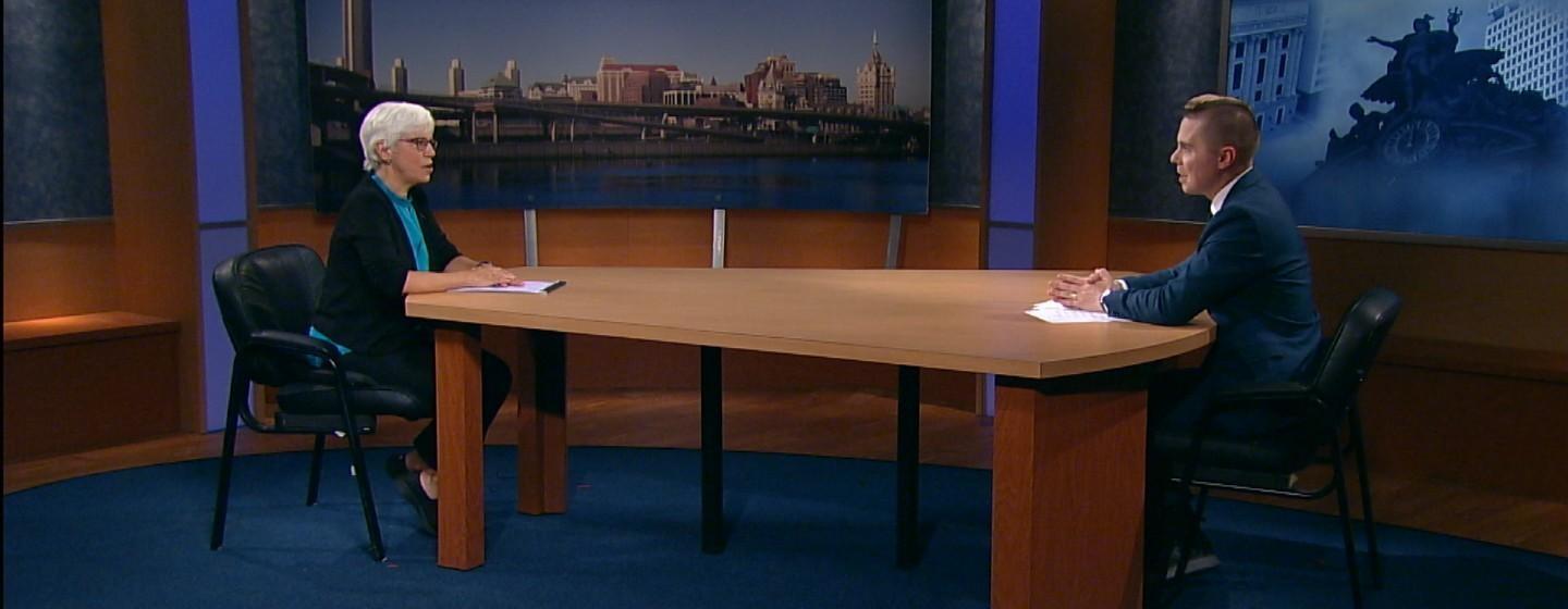 Karen Dewitt and Dan Clark sit socially distanced on the New York NOW set