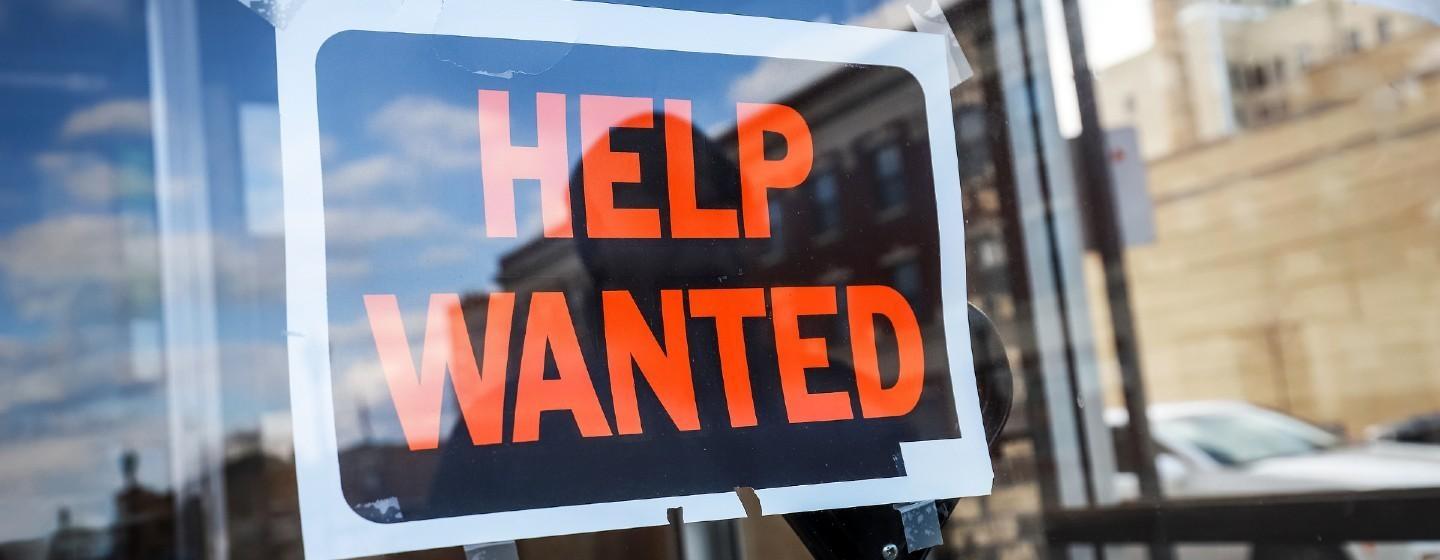 Help Wanted sign taped to a window