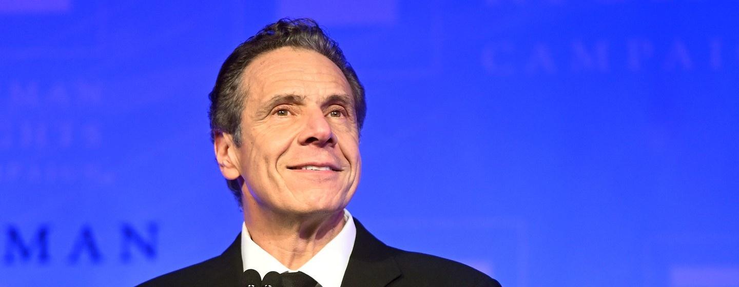 Governor Andrew Cuomo smiling on a blue background