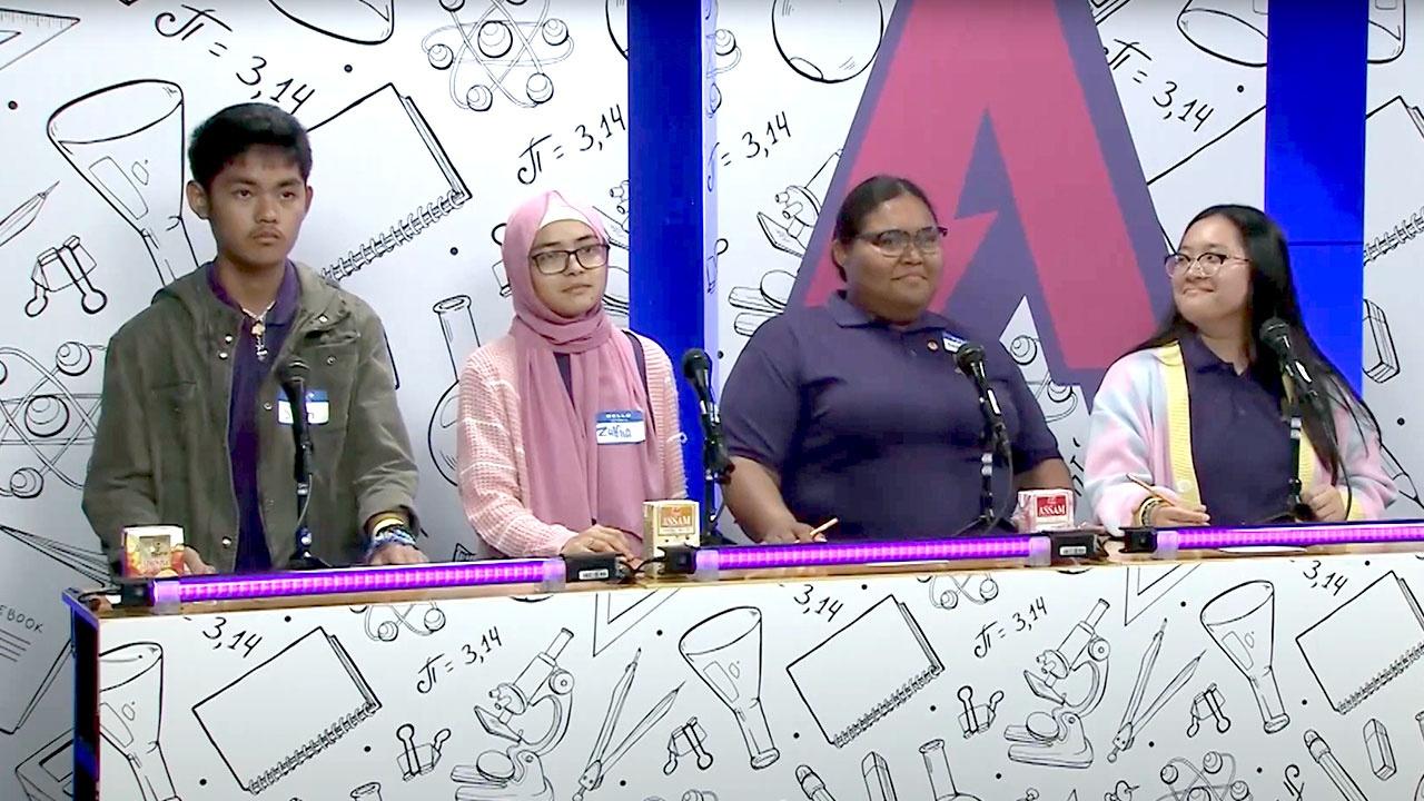 Four students are standing while they await their scores on set of the Academic Challenge Bowl