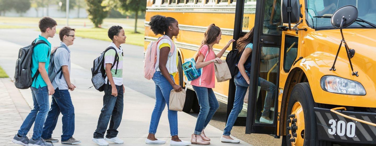 Students in a line walking into a yellow school bus.