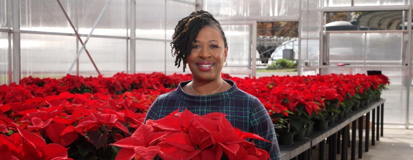 Deborah Holt Noel, host of NC Weekend holding a bright red poinsettia.