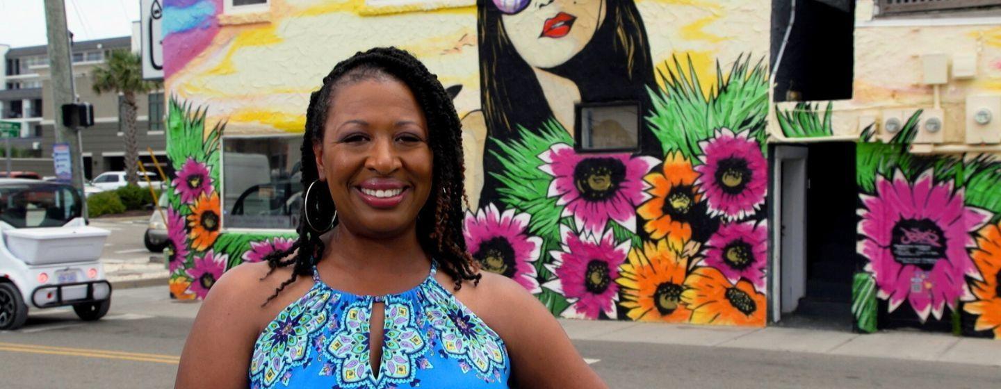 Deborah Holt Noel, host of NC Weekend in front of a mural at Carolina Beach.