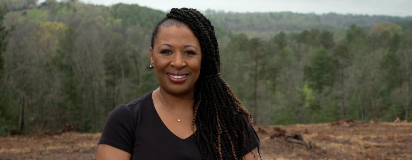 Host of NC Weekend, Deborah Holt Noel with a forest behind her.