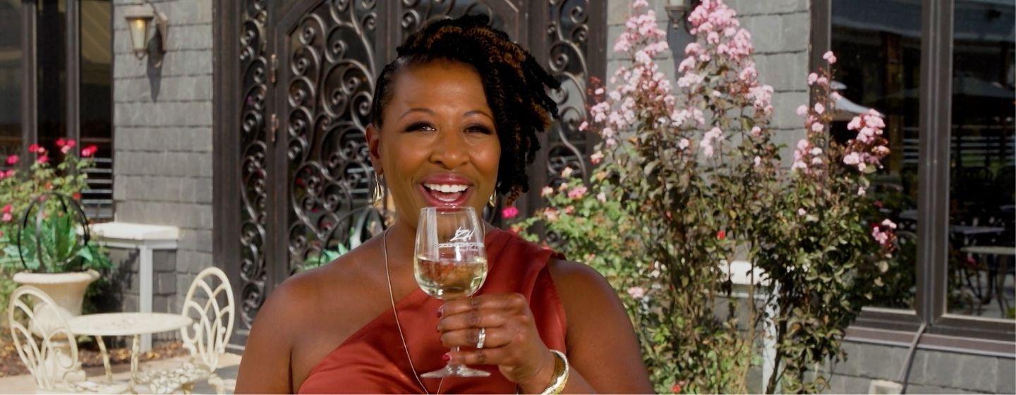 Deborah Holt Noel holding a wine glass up, about to take a sip.