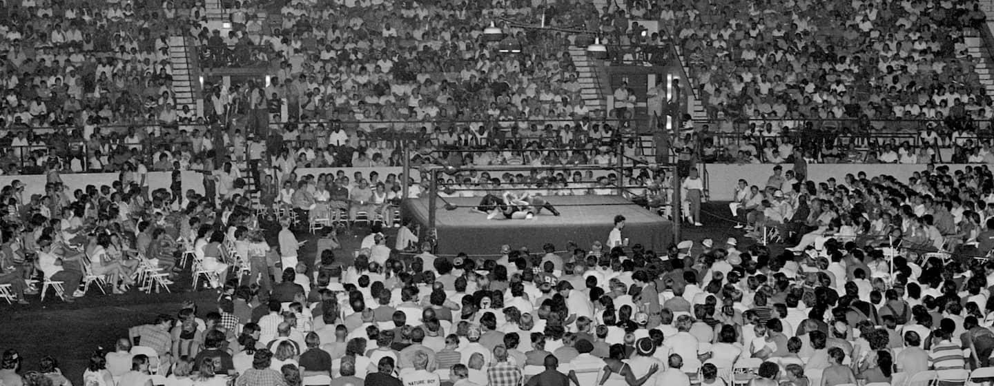 A black and white photo of a massive crowd at Dorton Arena, around a wrestling ring in the middle.