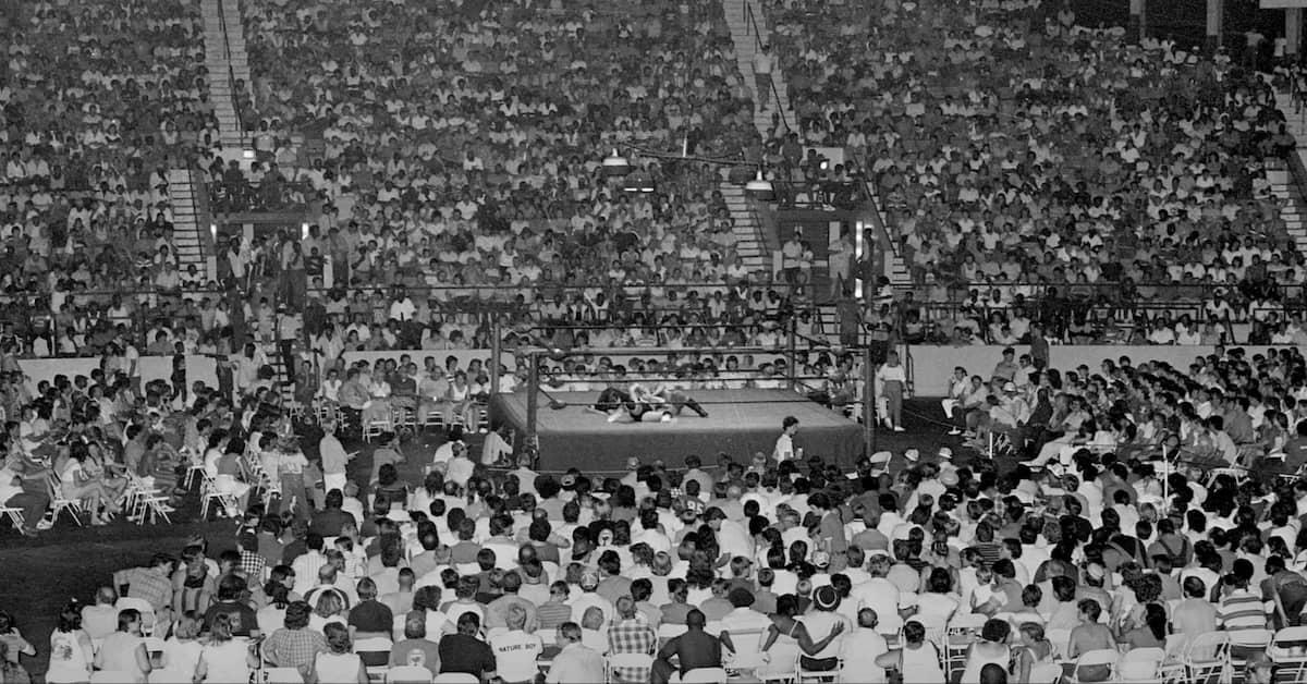 A black and white photo of a massive crowd at Dorton Arena, around a wrestling ring in the middle.