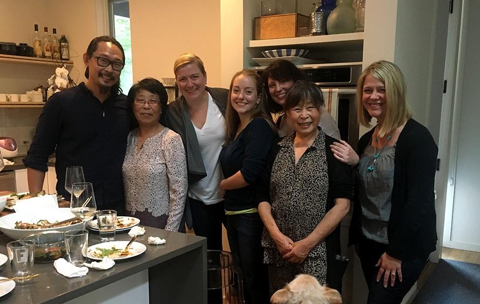 A group stands in Joe Kwon's kitchen. From left to right, host Joe Kwon, Kwon's Aunt Su, Chef Ashley Christensen, Kaitlyn Goalen, Kwon's wife Emily Meineke, Mama Kwon, and My Home NC's Heather Burgiss.