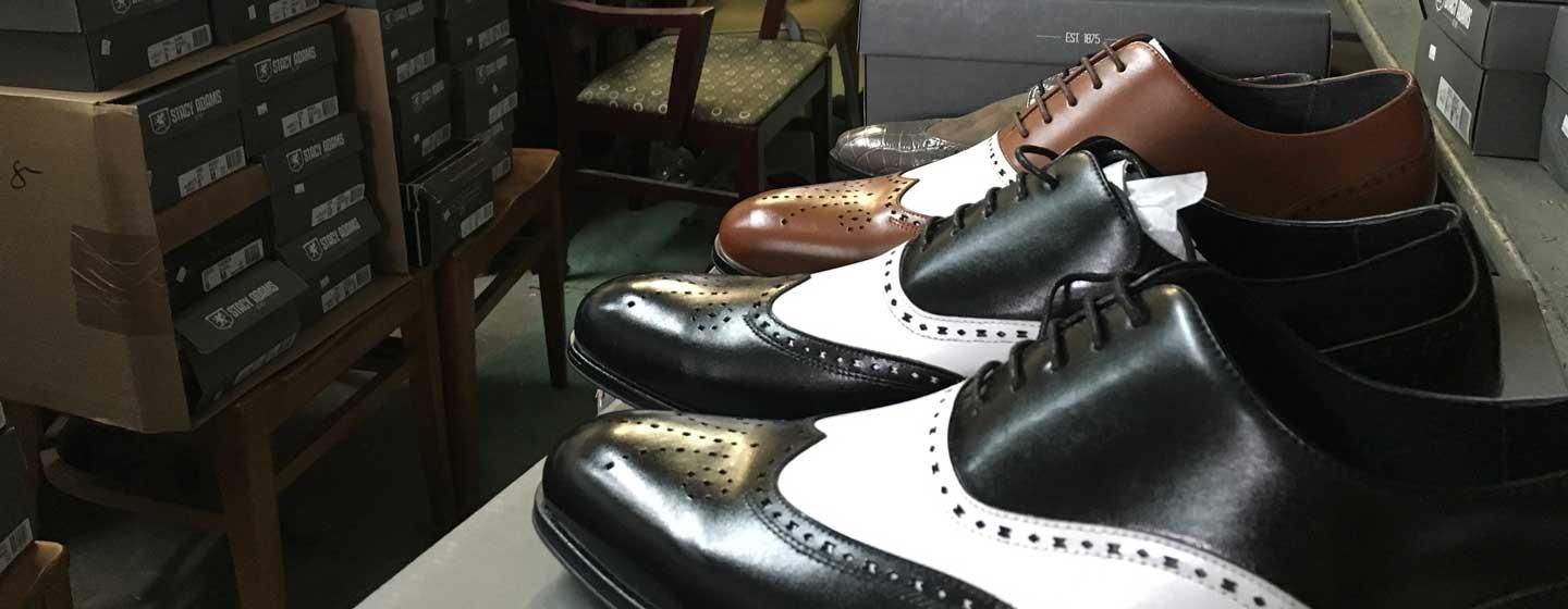 black, white and brown mens shoes lined up in a row and sitting on display stand